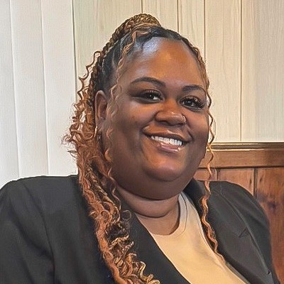 A women is smiling proudly while dressed in smart business attire