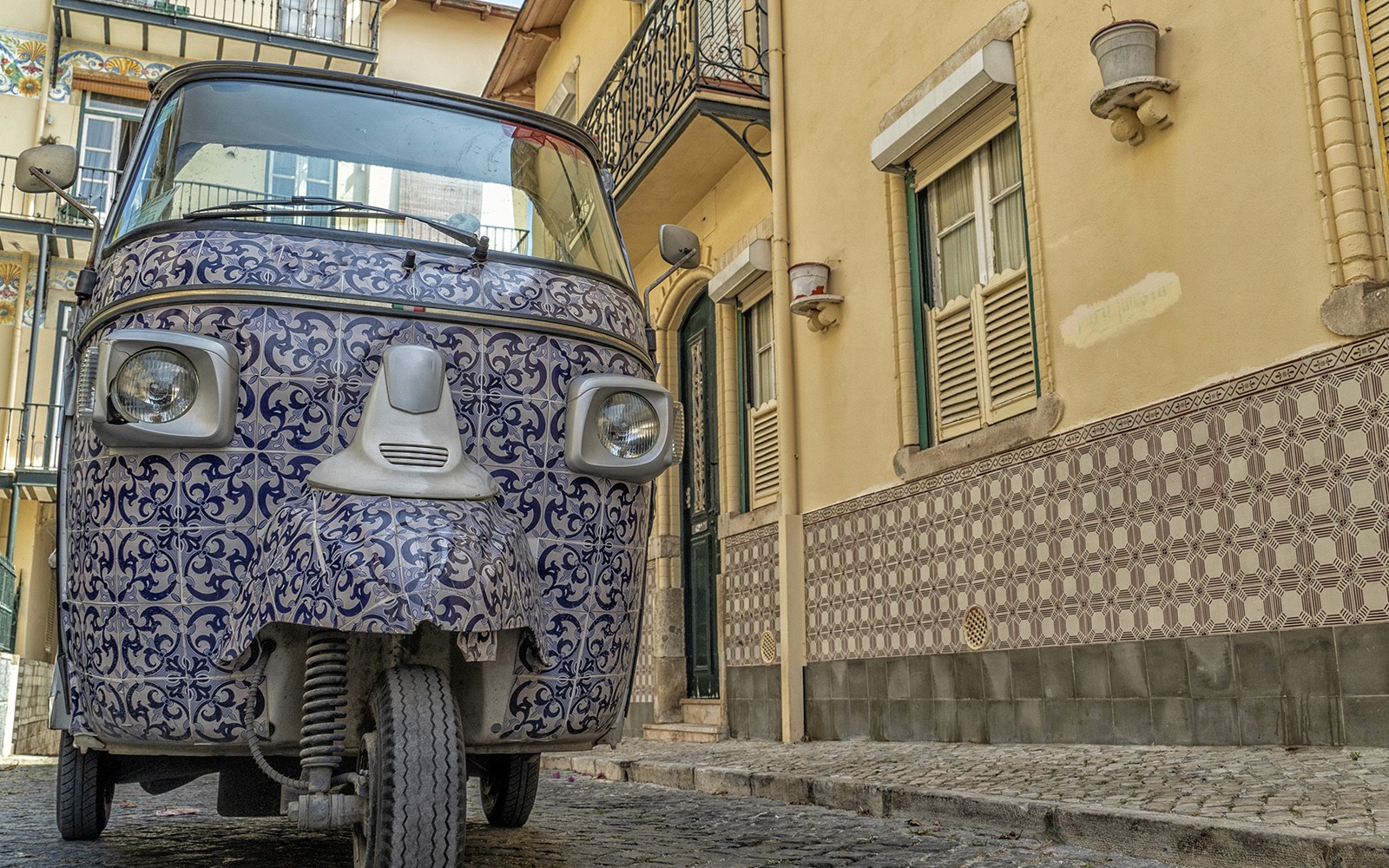 在历史街区的鹅卵石街道上,一辆装饰瓷砖的电动嘟嘟车。