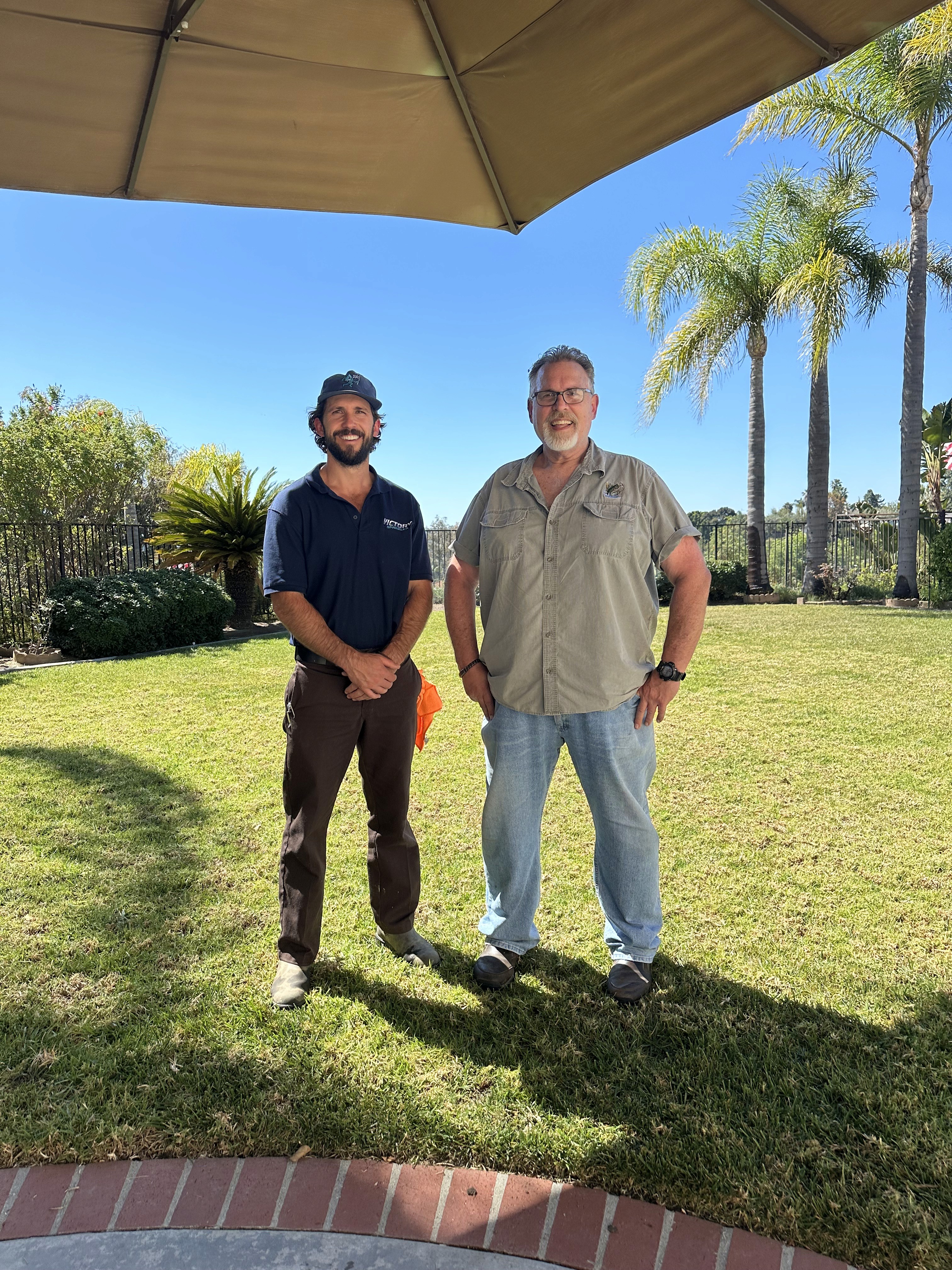 Owner Christian and customer Joe smiling in a front yard, representing a five-star service experience and successful sprinkler system repair.