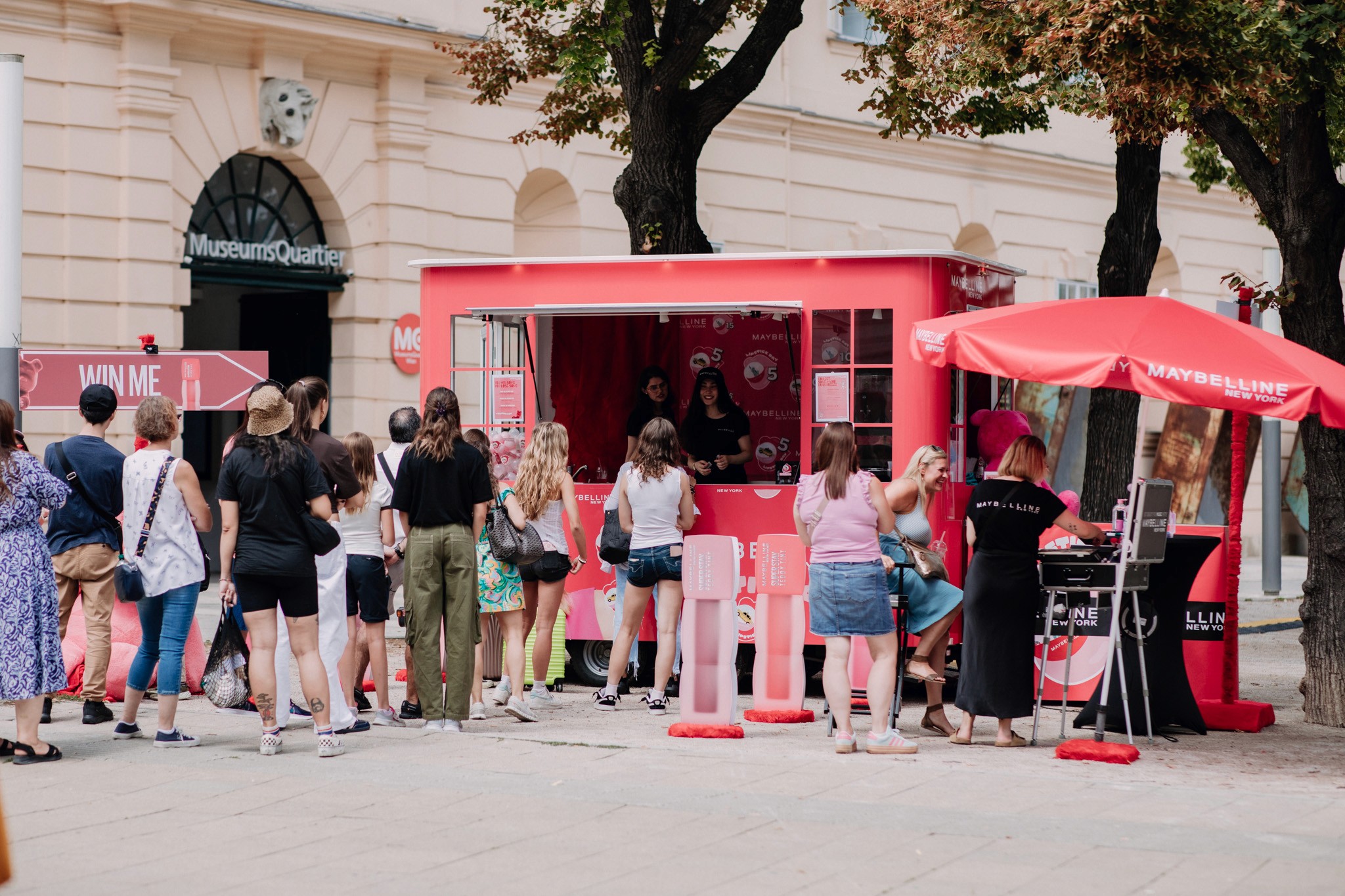 Maybellin lipstick Wagen, davor srtehen Leute und Schirme.