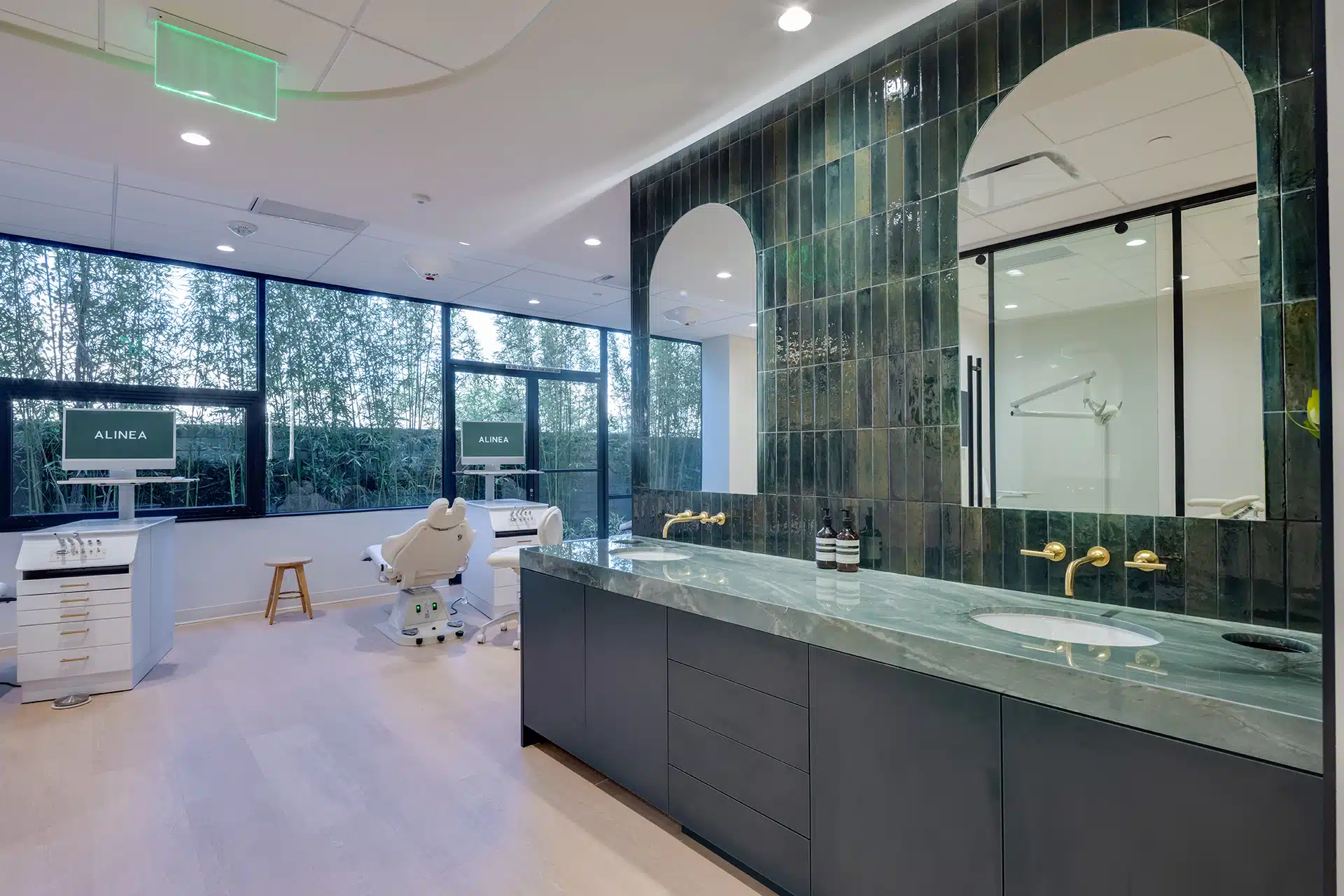 Modern clinic vanity with green tile wall, marble counter, and gold fixtures at Alinea Orthodontics.
