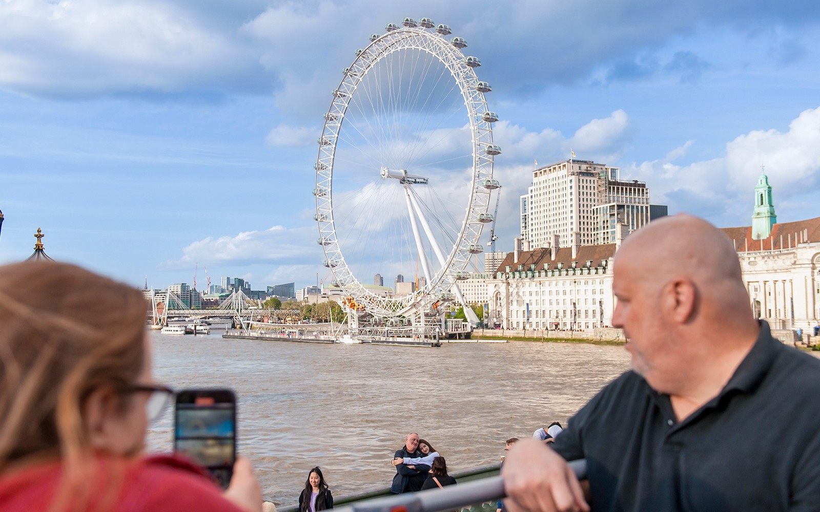 一对情侣在伦敦眼背景下拍照。
