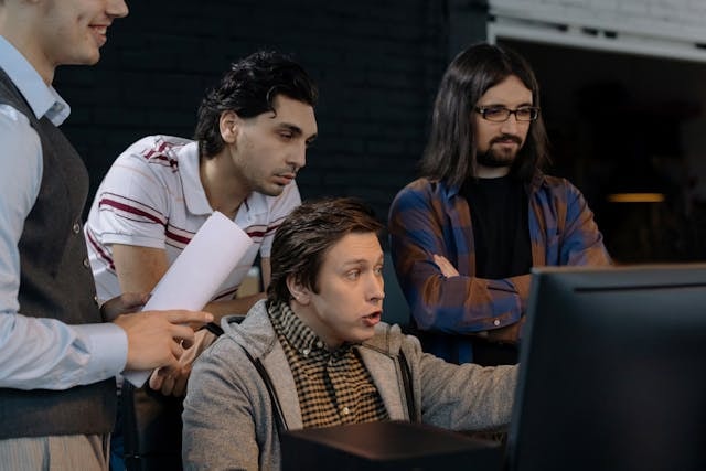Four men looking at a computer screen