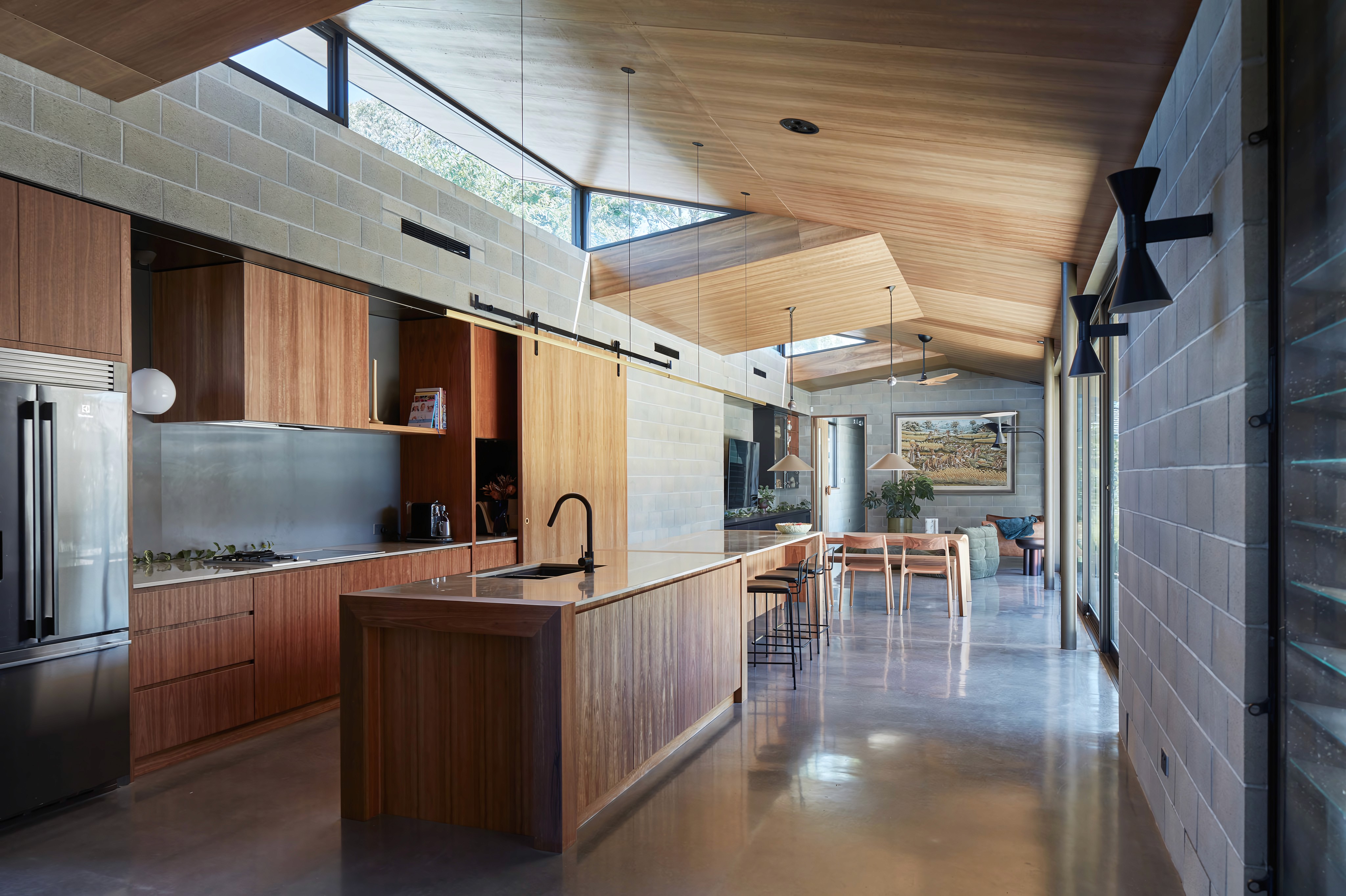 Modern bathroom featuring wooden cabinetry, a bathtub, a sleek sink, and natural light from a window.