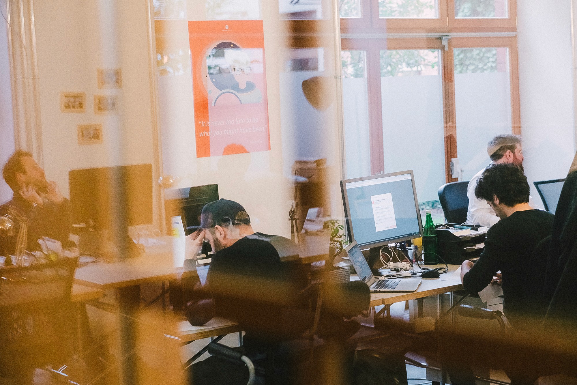 Mehrere Personen arbeiten konzentriert an Computern in einem modernen Co-Working-Space mit Glaswänden.