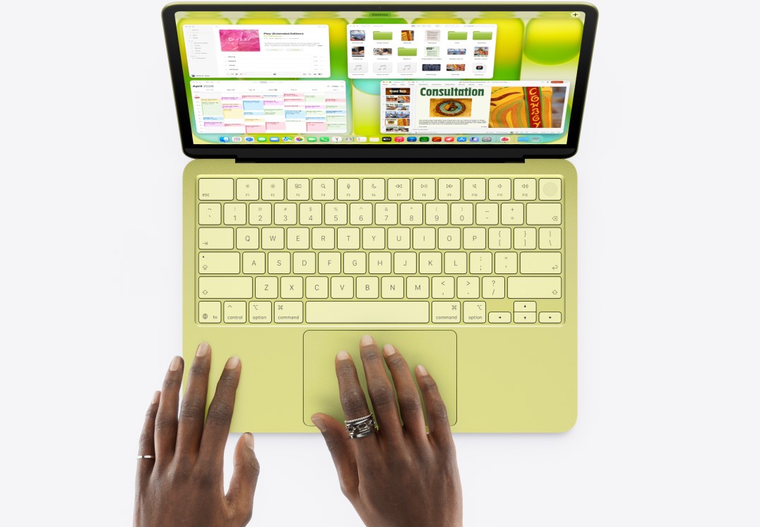 A high-angle photograph looking down as a student with dark skin, wearing a simple wedding band and other rings, places their hands on the trackpad and palm rest of an open, light green Apple MacBook Neo. The screen is active, showing the specific macOS Stage Manager interface with multiple windows for a calendar, photos, notes, and a consultation document. This image effectively shows the interaction with the high-value, A18 Pro-powered MacBook Neo that is the top recommendation for student success in Canada.