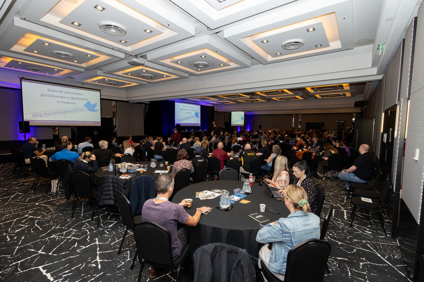 Conference room filled with people sitting at round tables