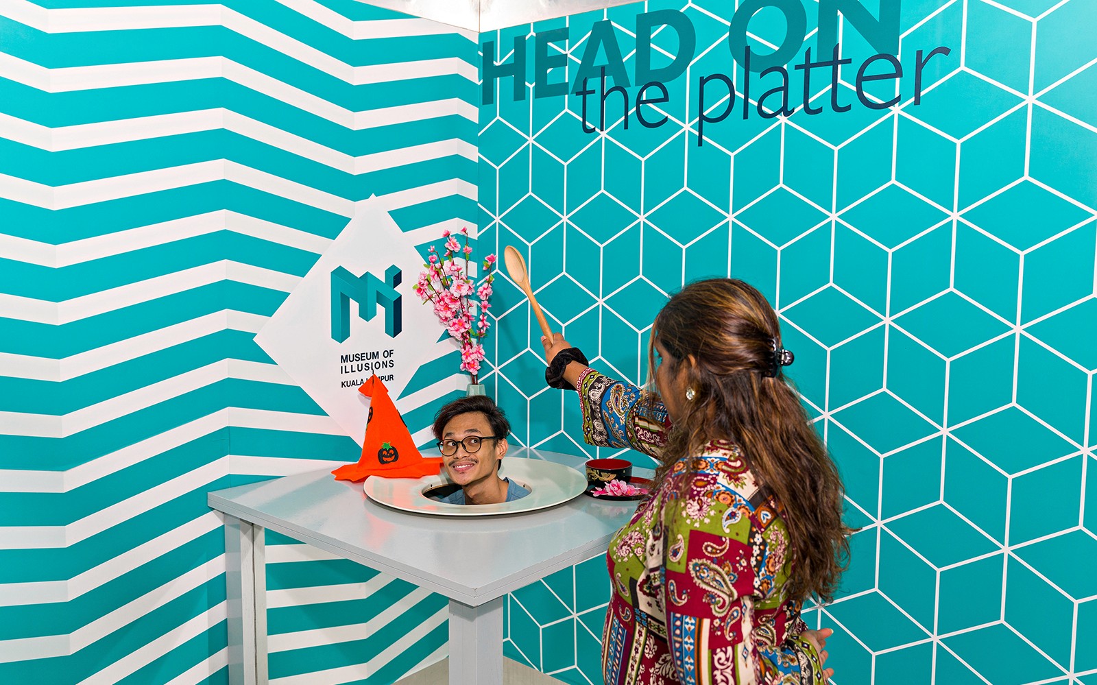 クアラルンプールのイリュージョン博物館で、頭がお皿に載った錯覚を体験している人。