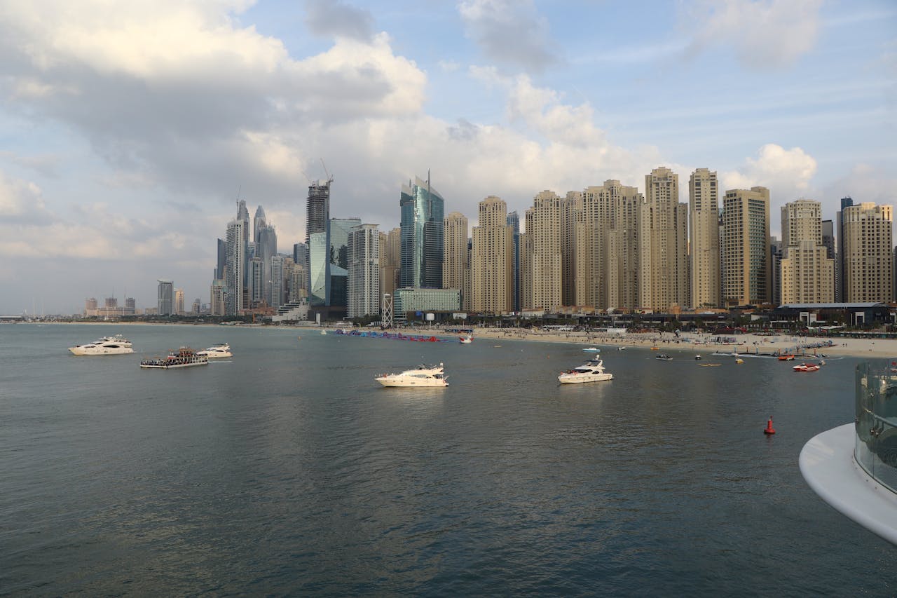 Boats cruising across the sea in front of Dubai’s city skyline and coastline during things to do in Dubai with family.