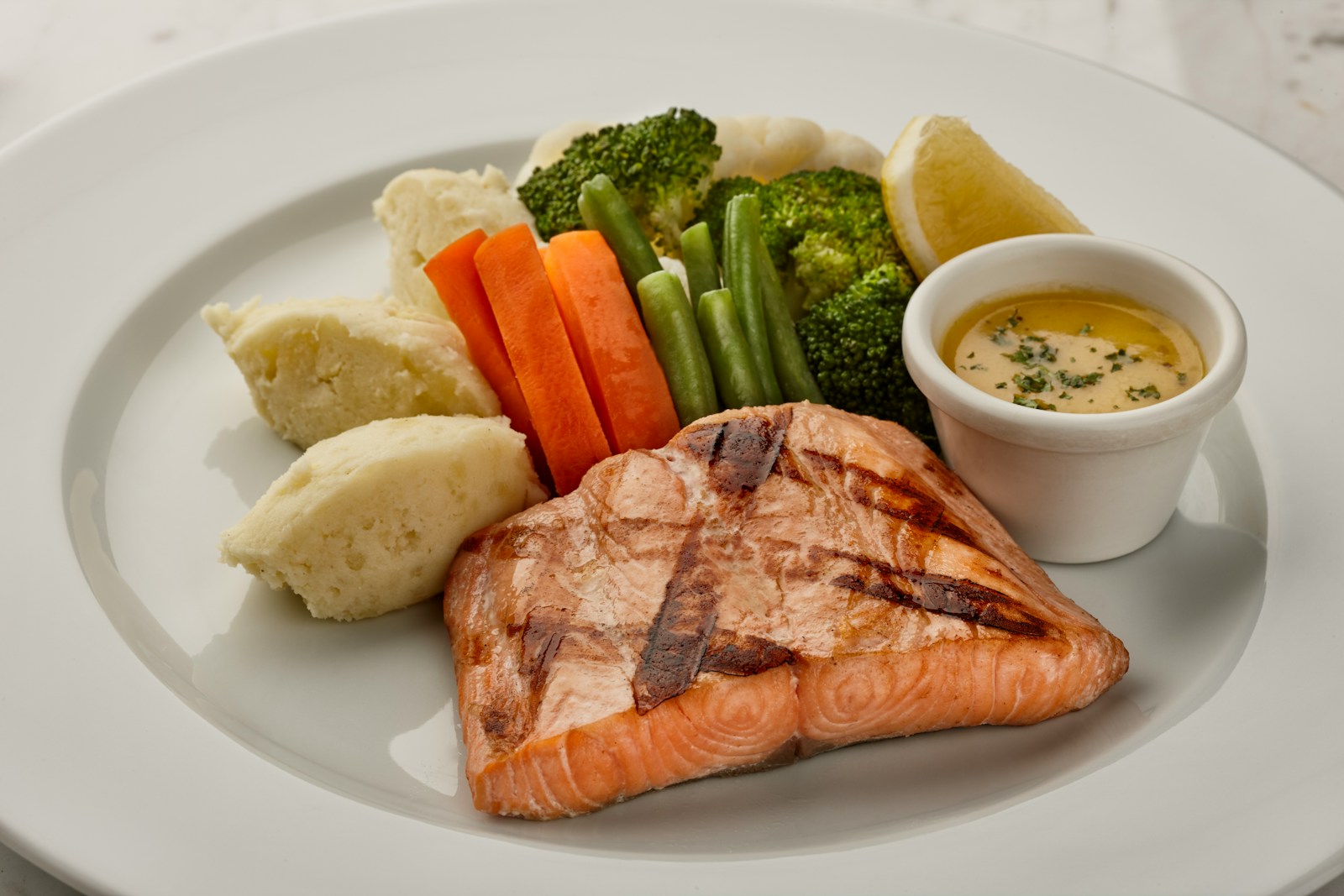 A plate of grilled salmon served with mashed potato, carrots, green beans, and broccoli — a balanced, protein-rich meal.