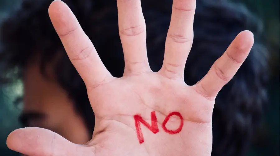 Ragazzo con mano alzata e scritta NO sul palmo, simbolo di disagio, sfiducia e mancanza di direzione nei giovani di oggi, superabile attraverso campi estivi educativi e crescita personale in natura
