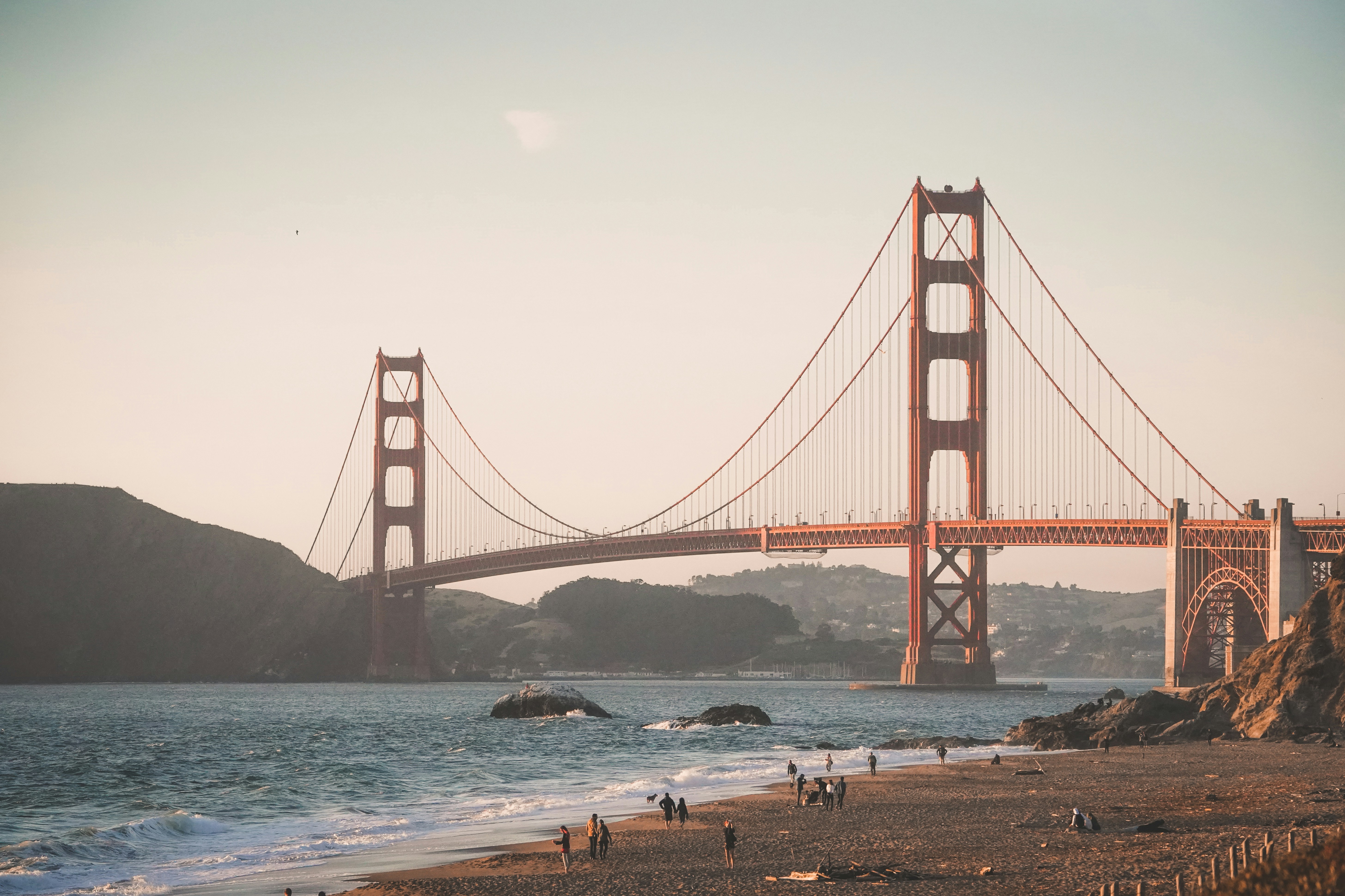 people walking near red bridge on body of water during daytime photo