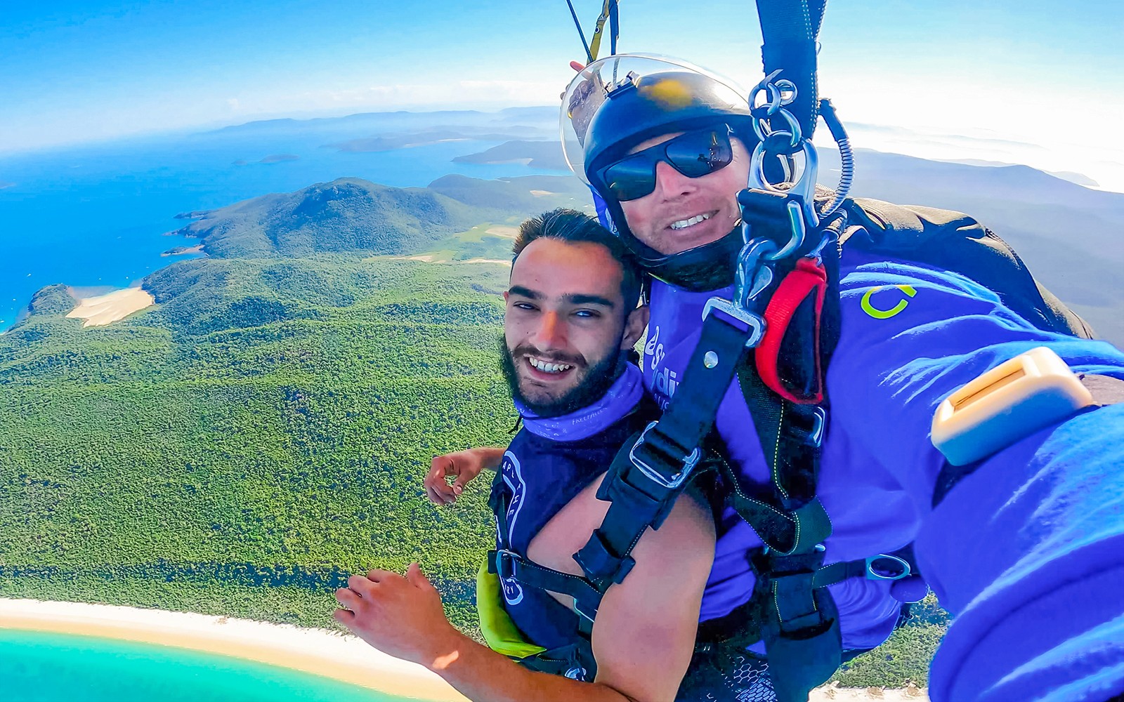 צונחים בטנדם מעל איירלי ביצ', מציגים את מי הטורקיז ונופי הצמחייה הפורחים מתחת.
