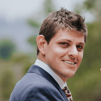 man in black suit jacket holding white ceramic mug