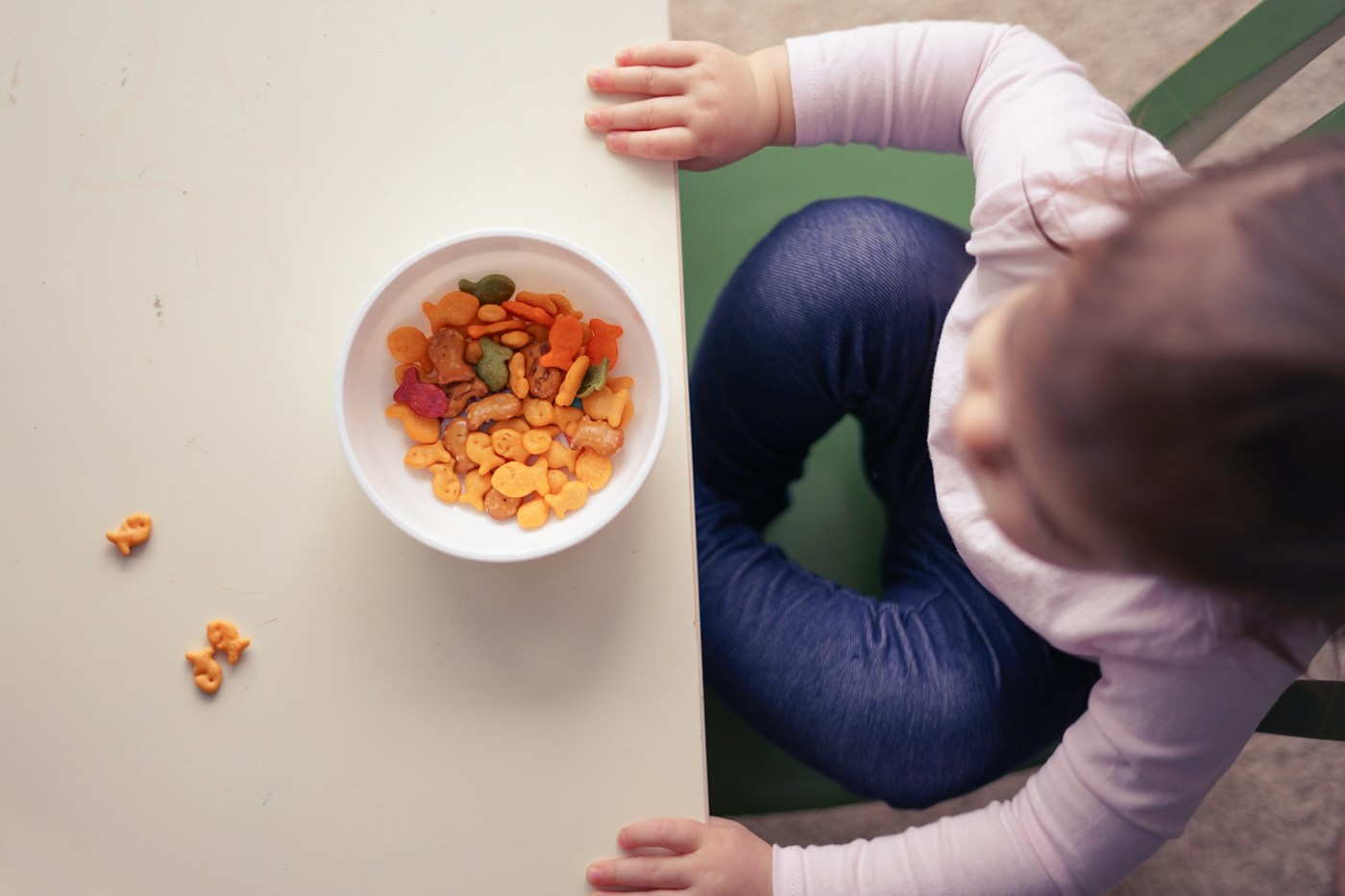 A toddler at a table exploring a bowl of snacks, illustrating gentle, low-pressure approaches to picky eating
