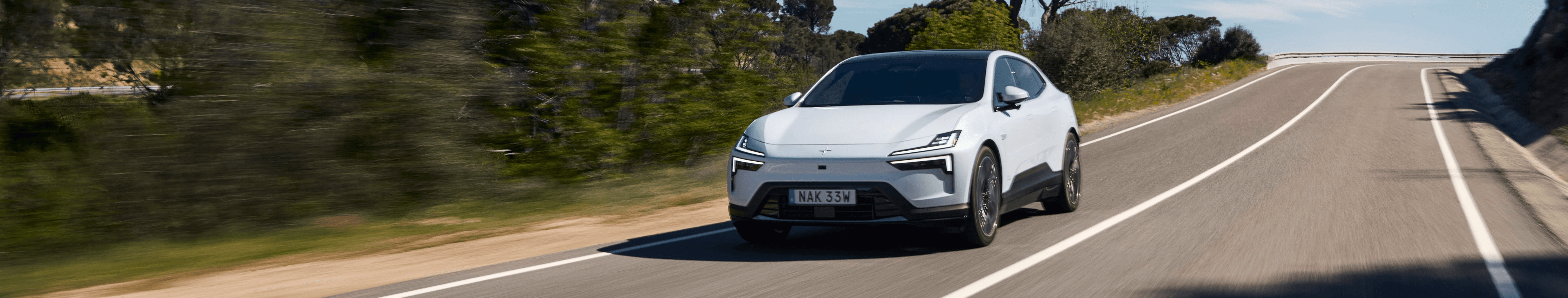 Polestar 4 blanche sur route ouverte, SUV coupé électrique en circulation par beau temps