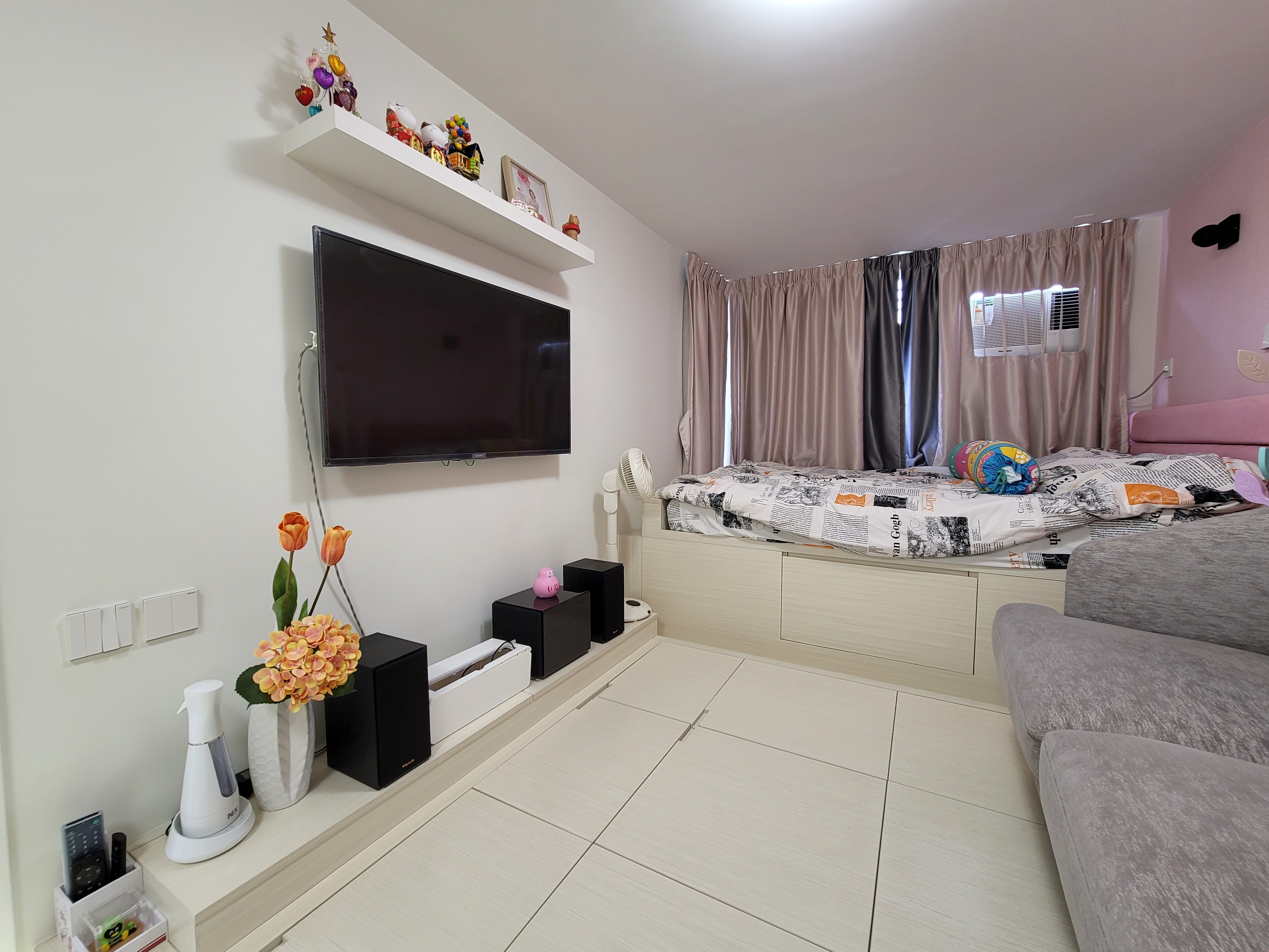 Wall-mounted television above white built-in cabinetry and floating shelf with decorative items in a Hoi Tat Estate living room design.