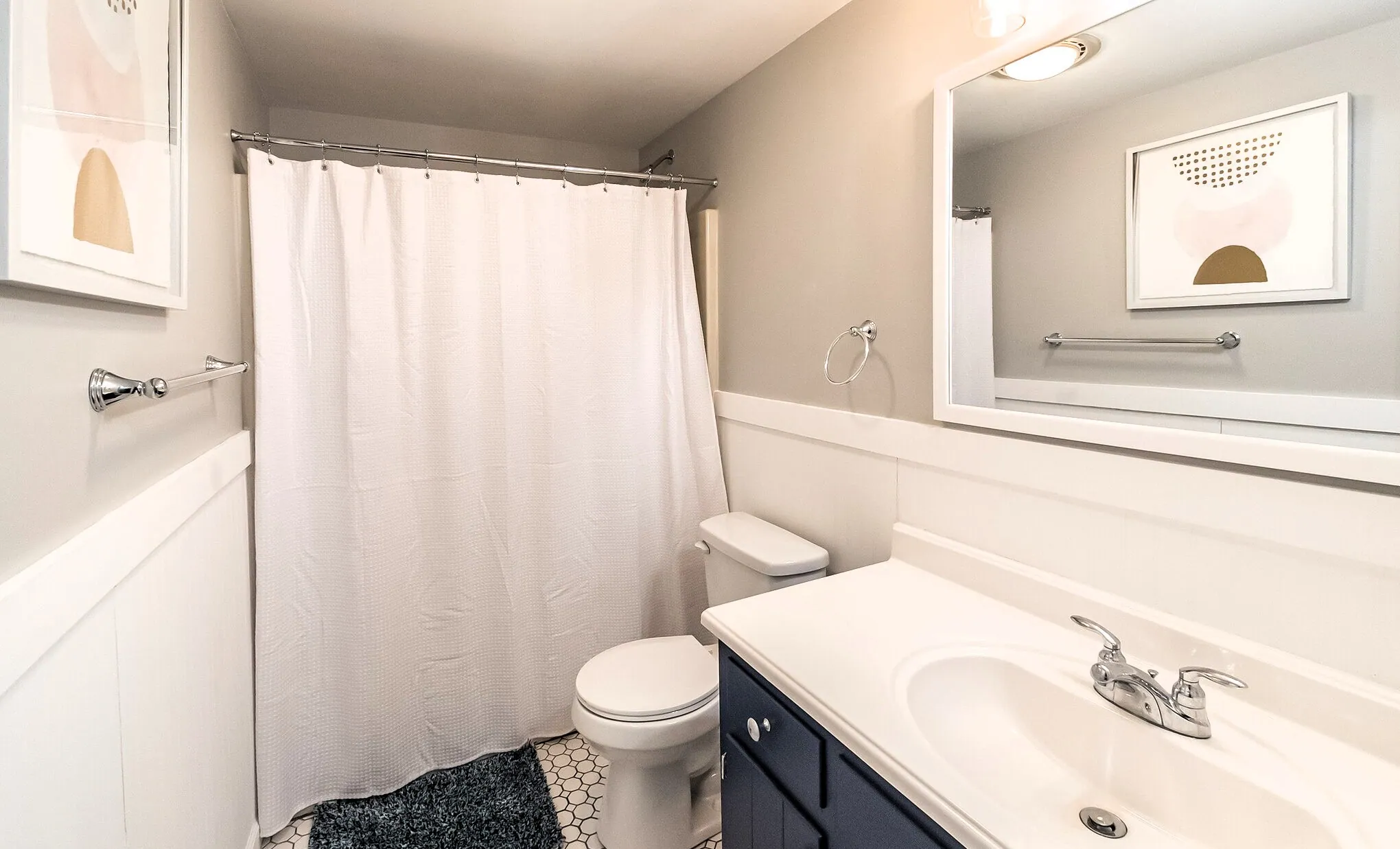 Upstairs full bathroom with tub shower, navy vanity and hex tile floor at Beechwood Bliss