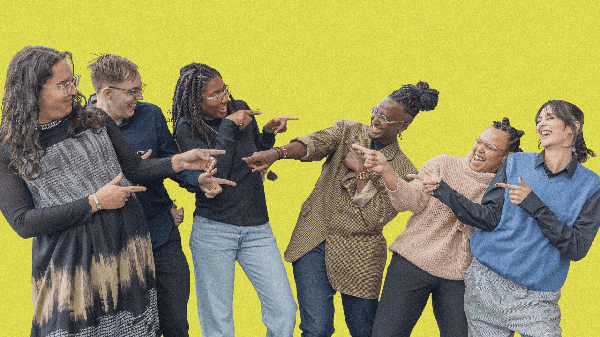 A diverse group of six people pose playfully against a bright yellow background, engaging with each other.