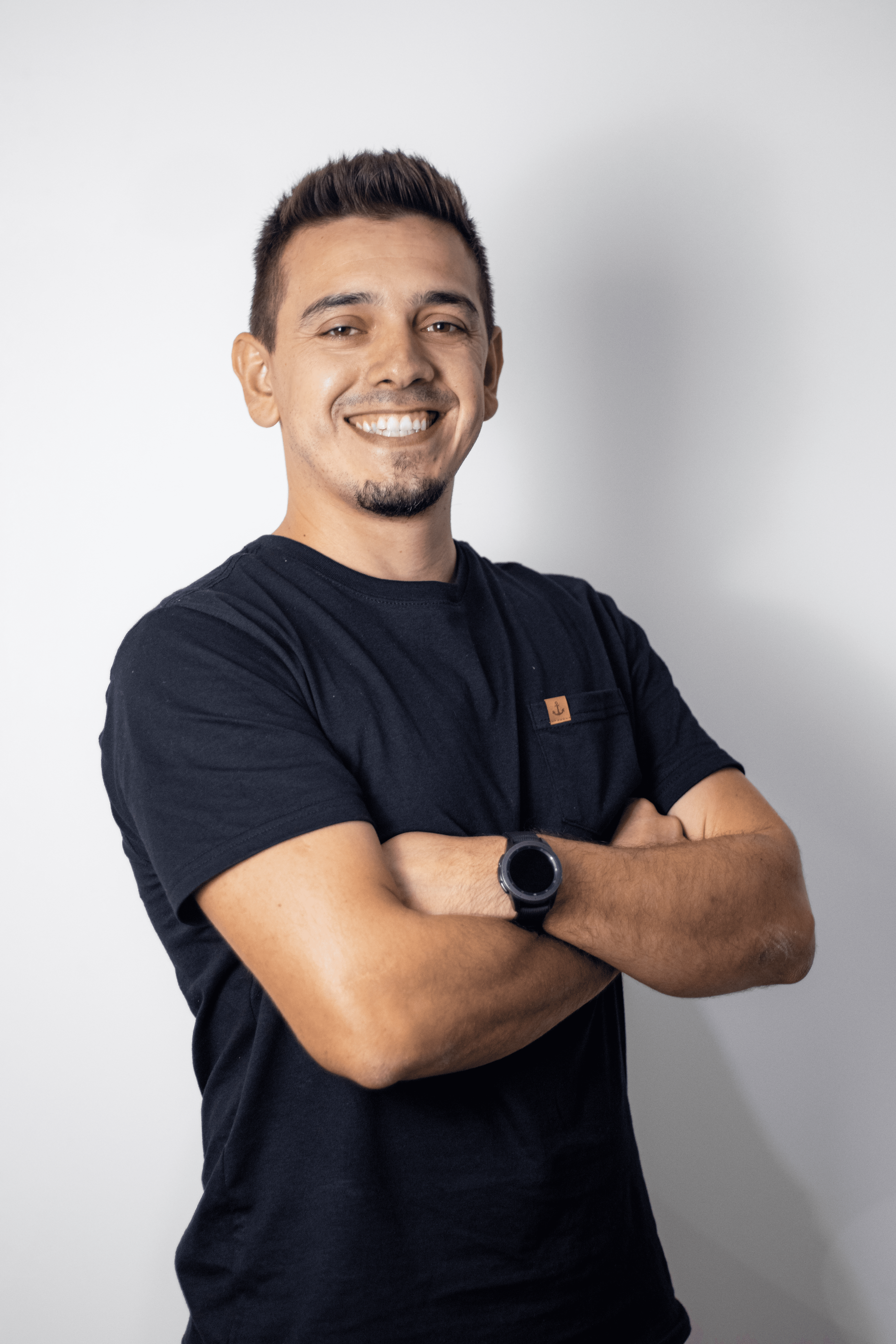 Foto do Guilherme Eid, home de camiseta azul marinho, de braços cruzados.