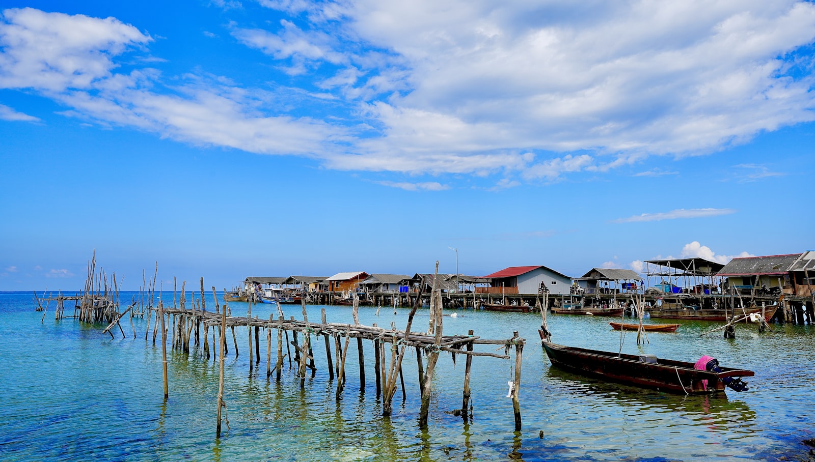 Bajau stilt village and weathered wooden jetty over shallow turquoise water