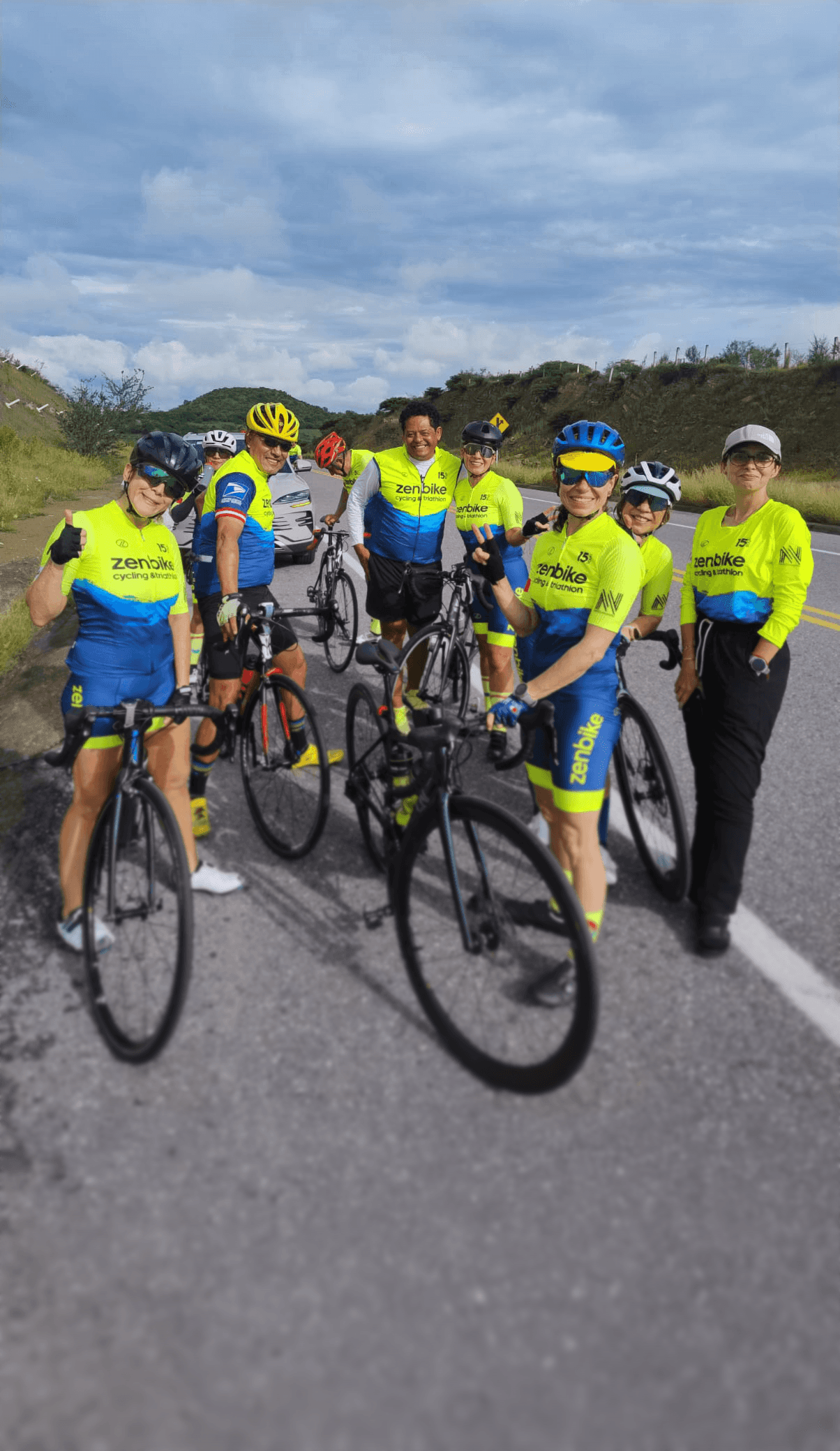 Ciclistas zenbike en carretera escénica durante entrenamiento grupal, celebrando los 15 años del equipo con uniforme conmemorativo.