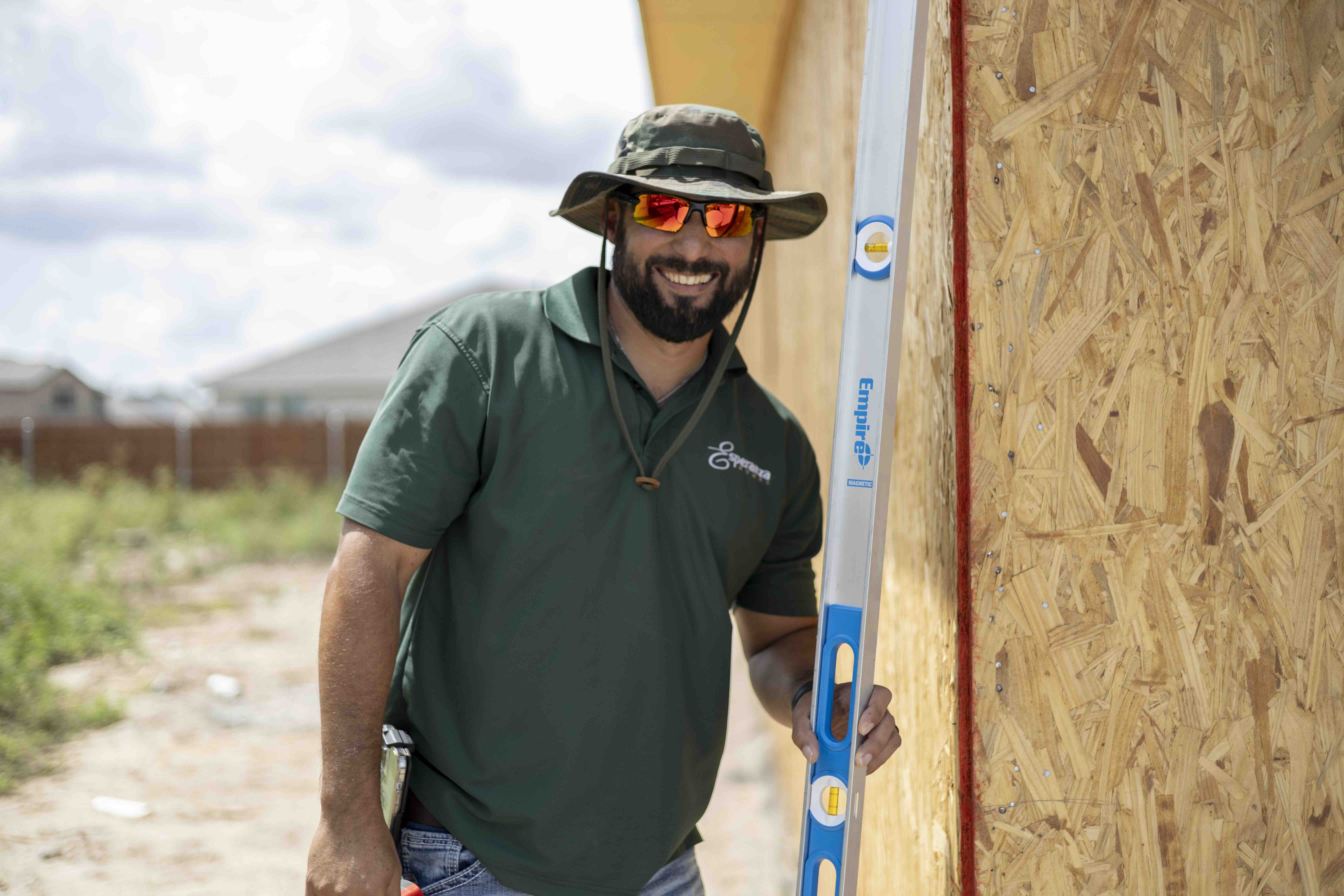 Esperanza Homes construction worker with level tool at building site in South Texas Rhodes Enterprises community