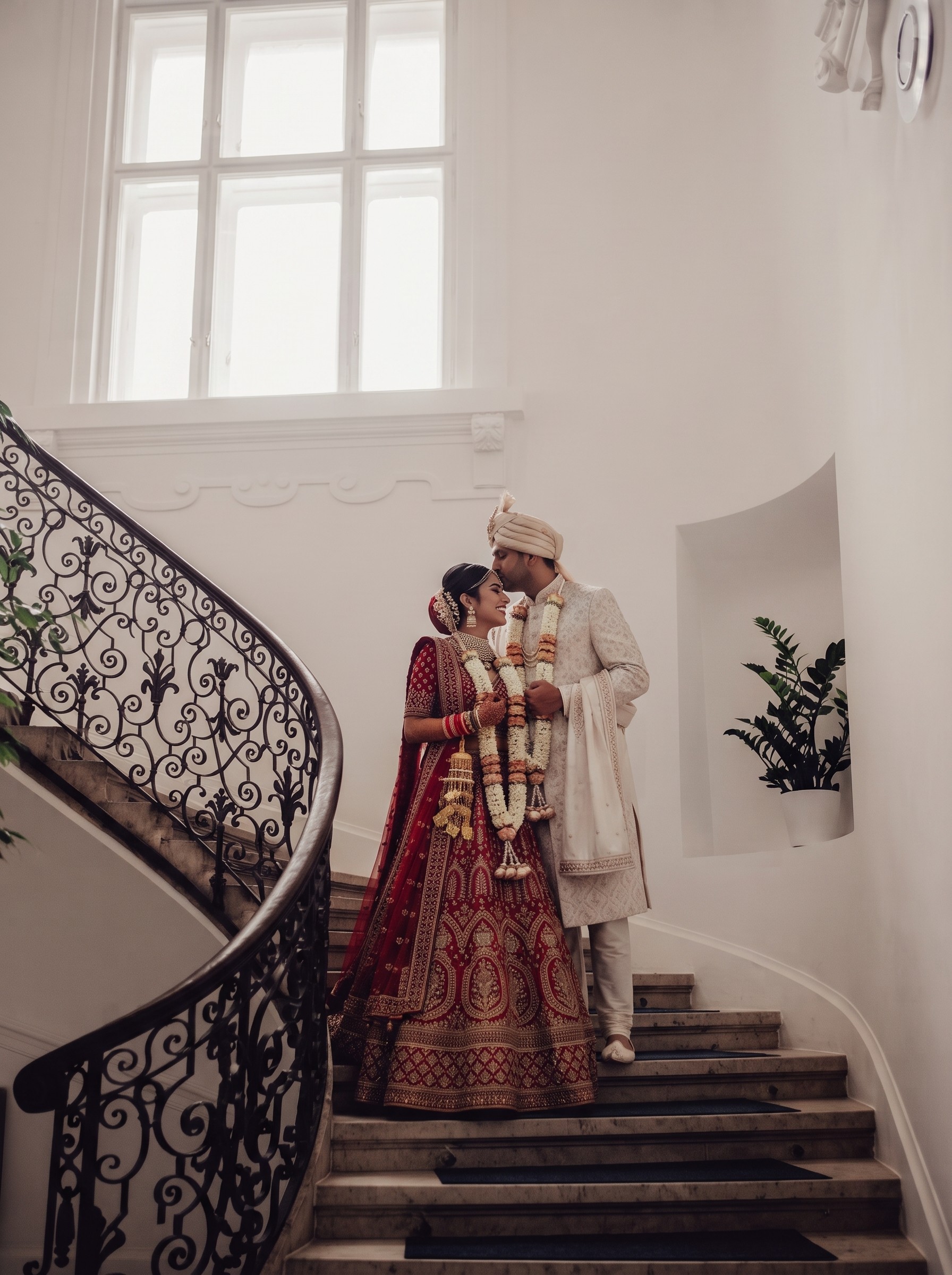 Newlyweds on ornate staircase with floral garlands.