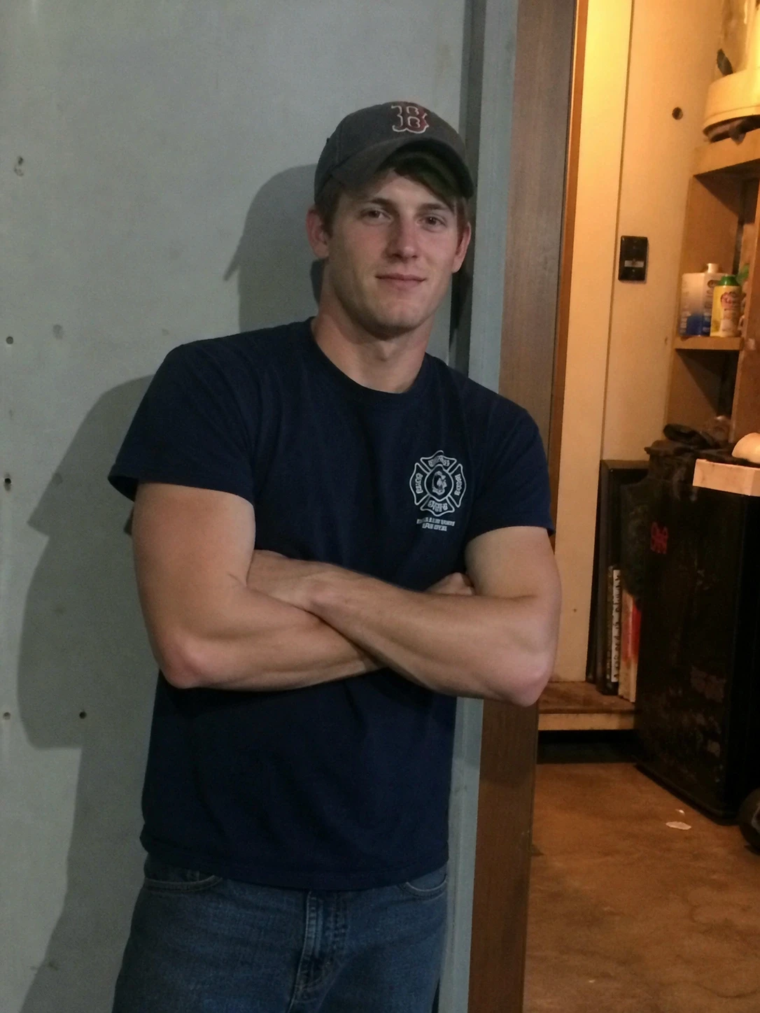 Young man in baseball cap standing with arms crossed