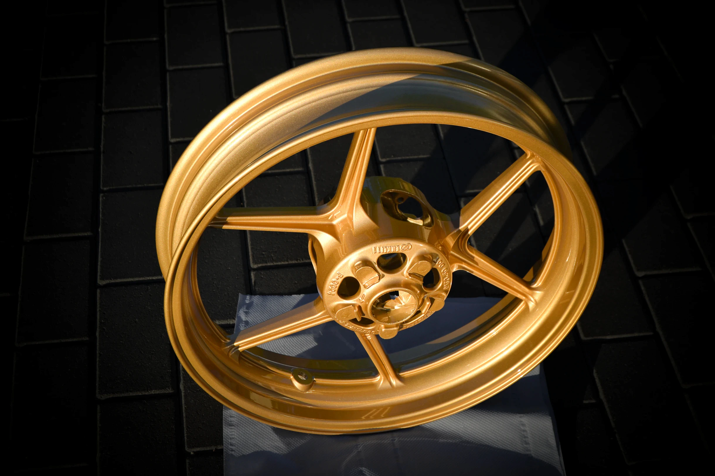 Goldfarbene Motorradfelge aus schräger Perspektive bei AT Plus.