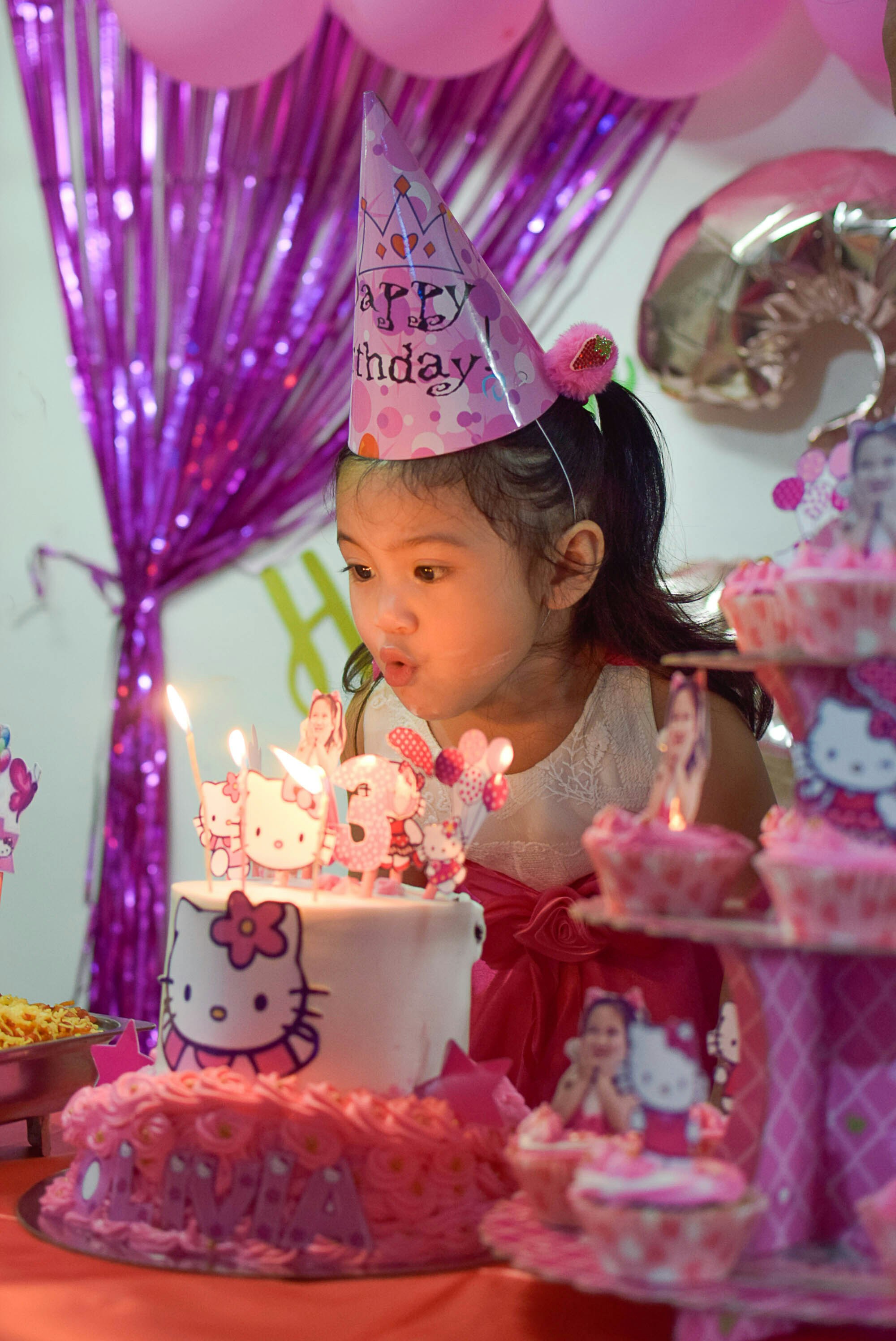 a little girl blowing out candles on a cake