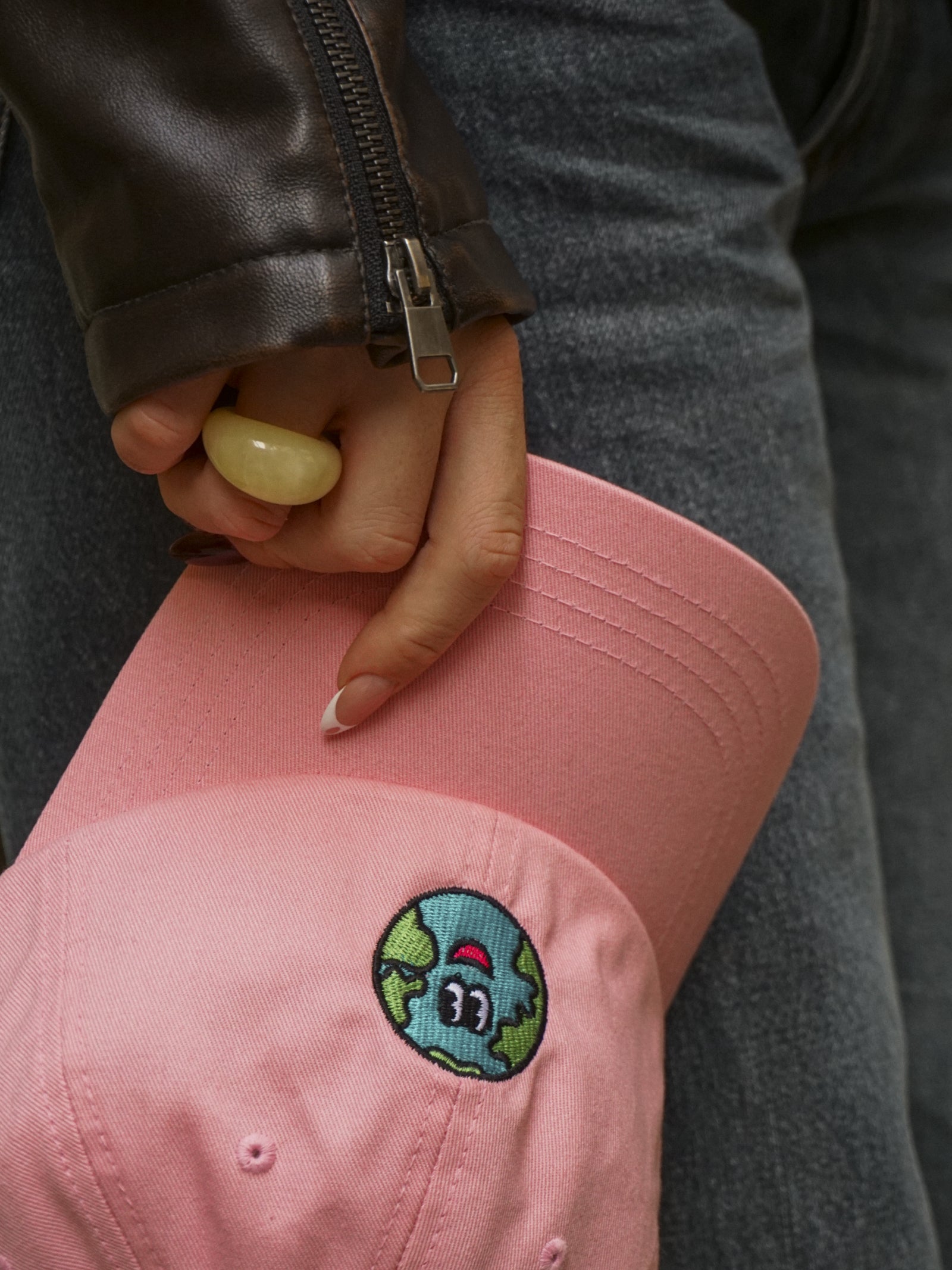 Person holding a pink cap with a colorful patch on a blurred background