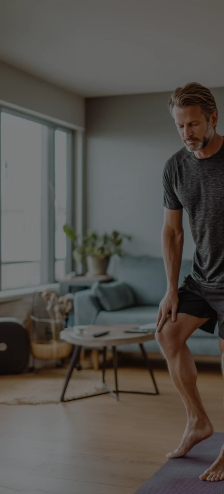 Man with knee pain rubbing knee in lving room