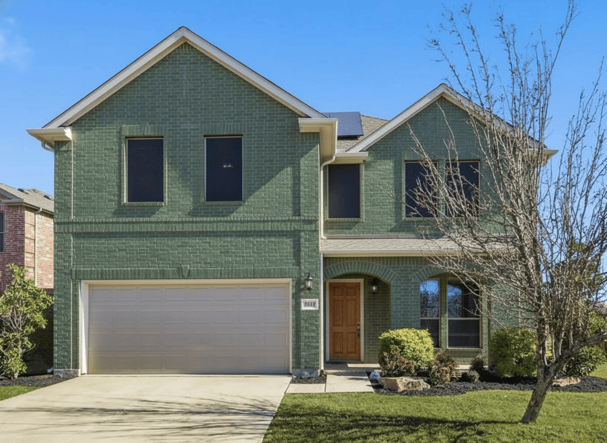 Same brick house painted deep sage green with white trim and natural wood front door