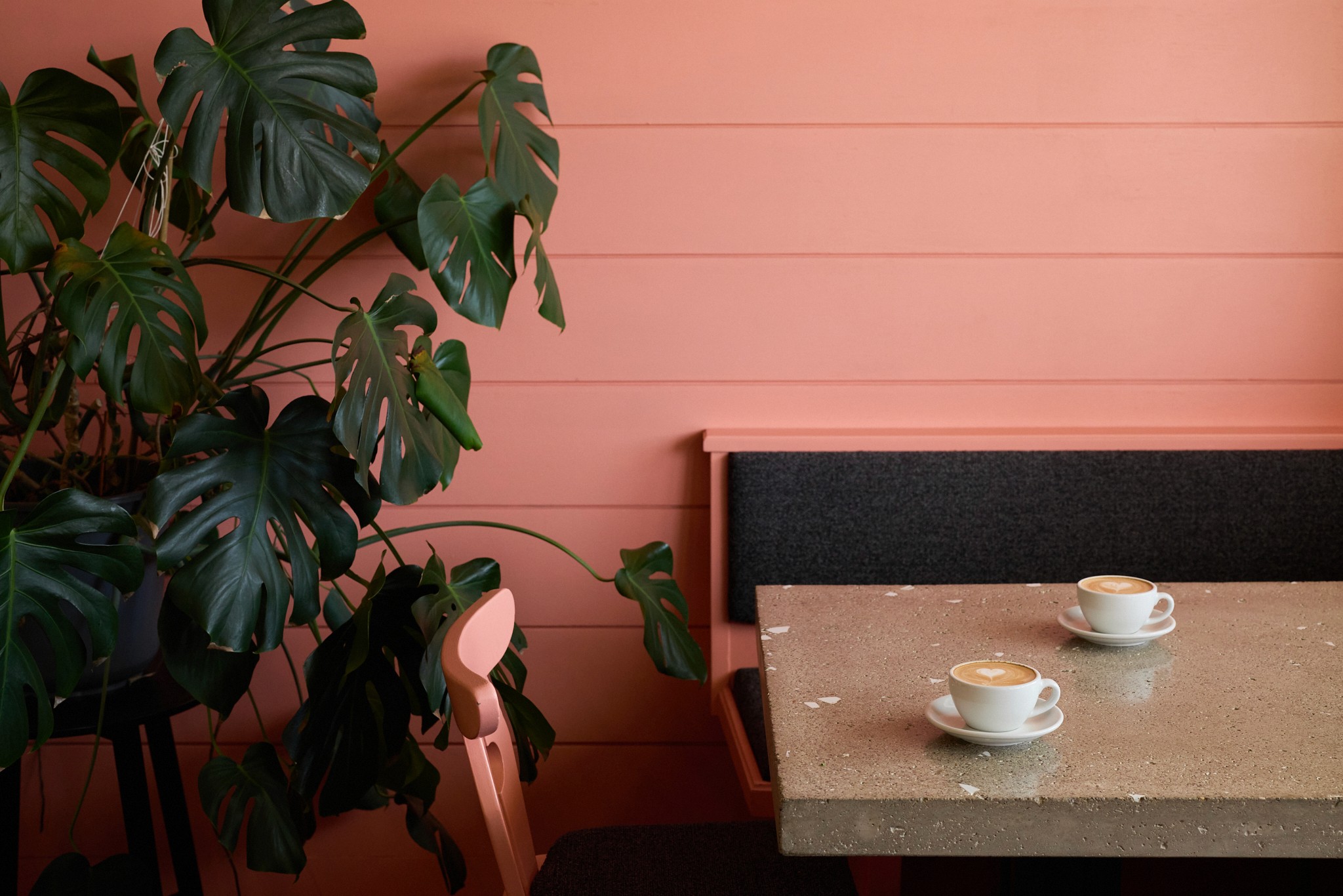 lachsrosa café mit betontisch und bänke und cappuccini