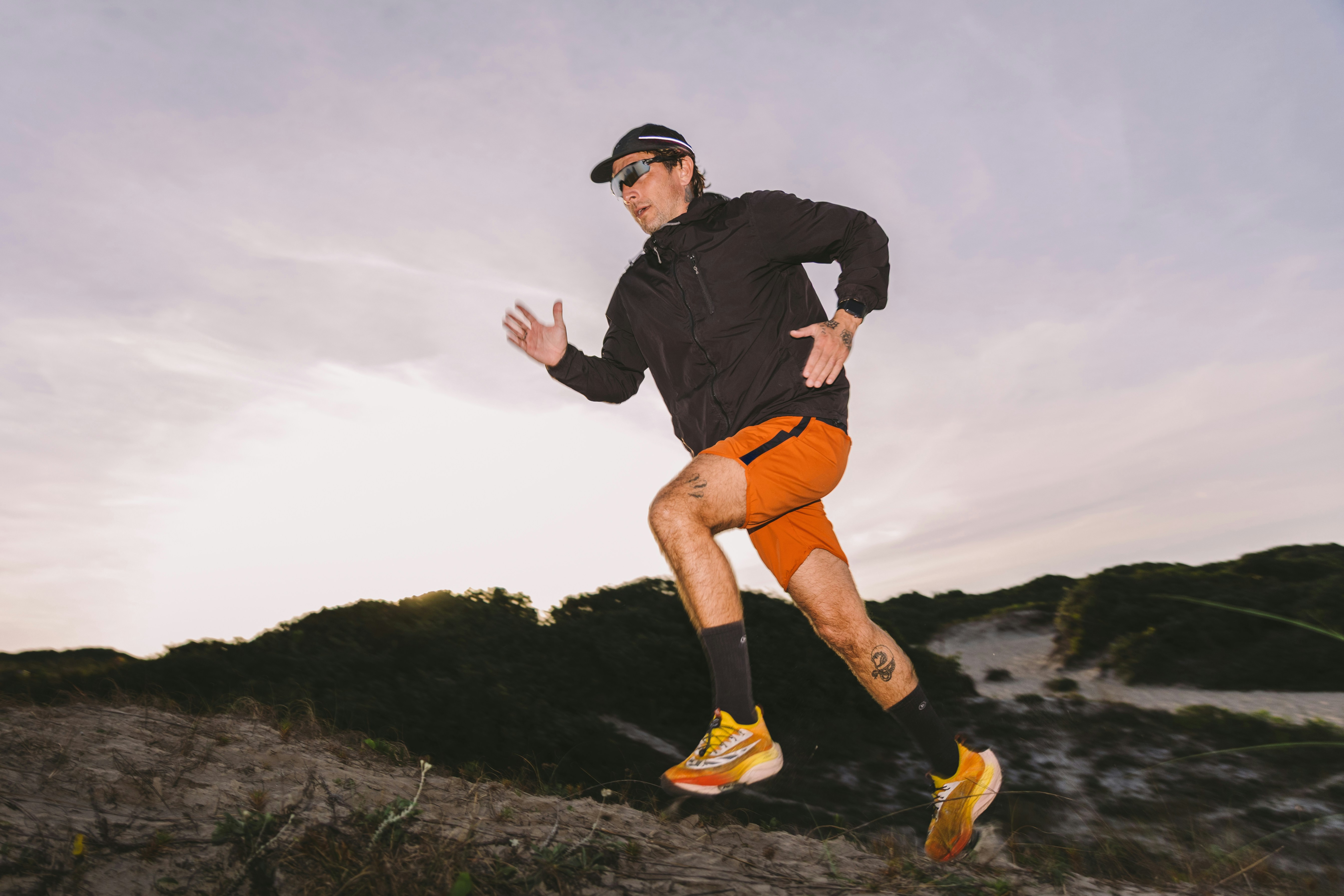 man running up a hill in bright-coloured shorts and trainers