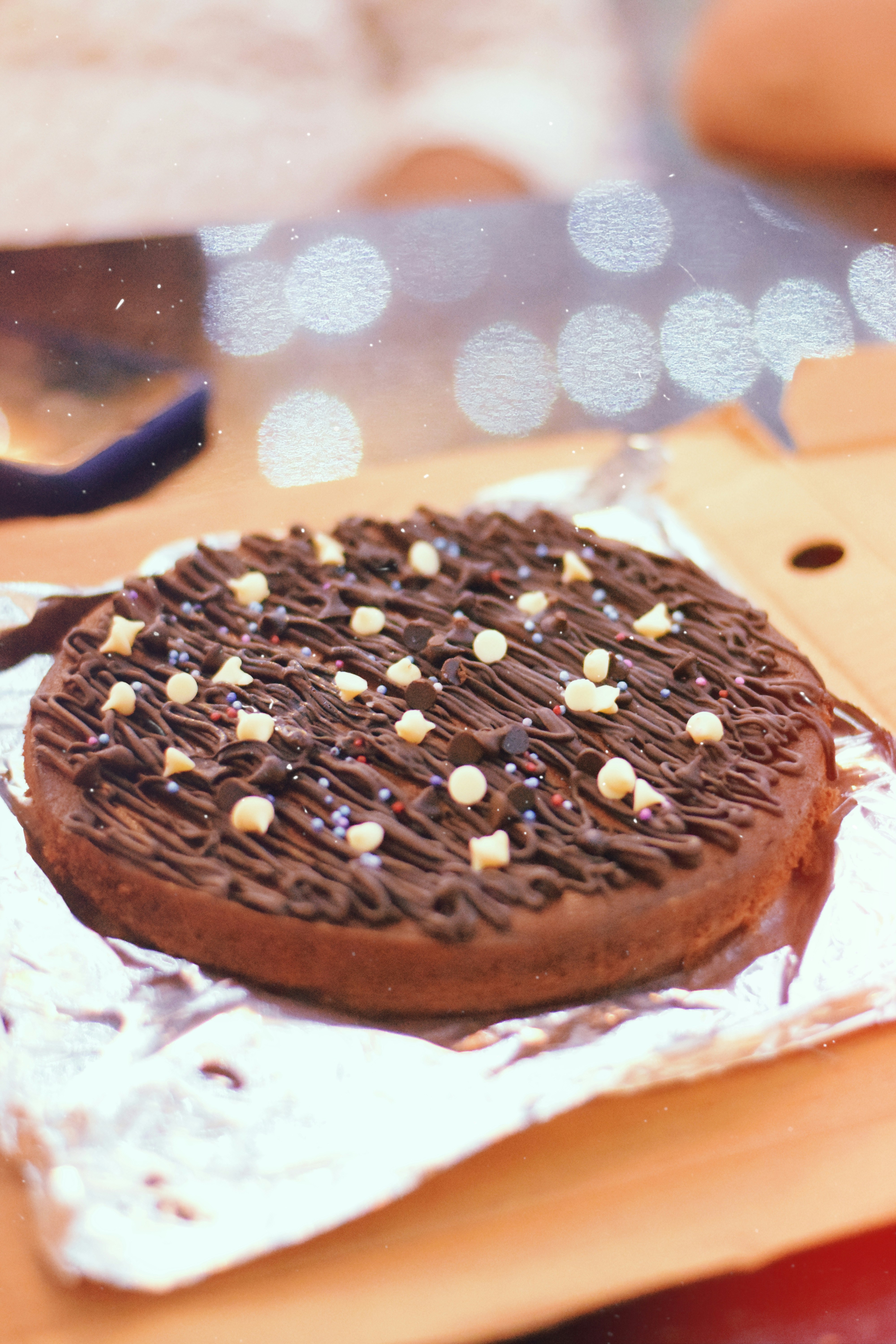 A chocolate cookie with white sprinkles on a piece of aluminum foil