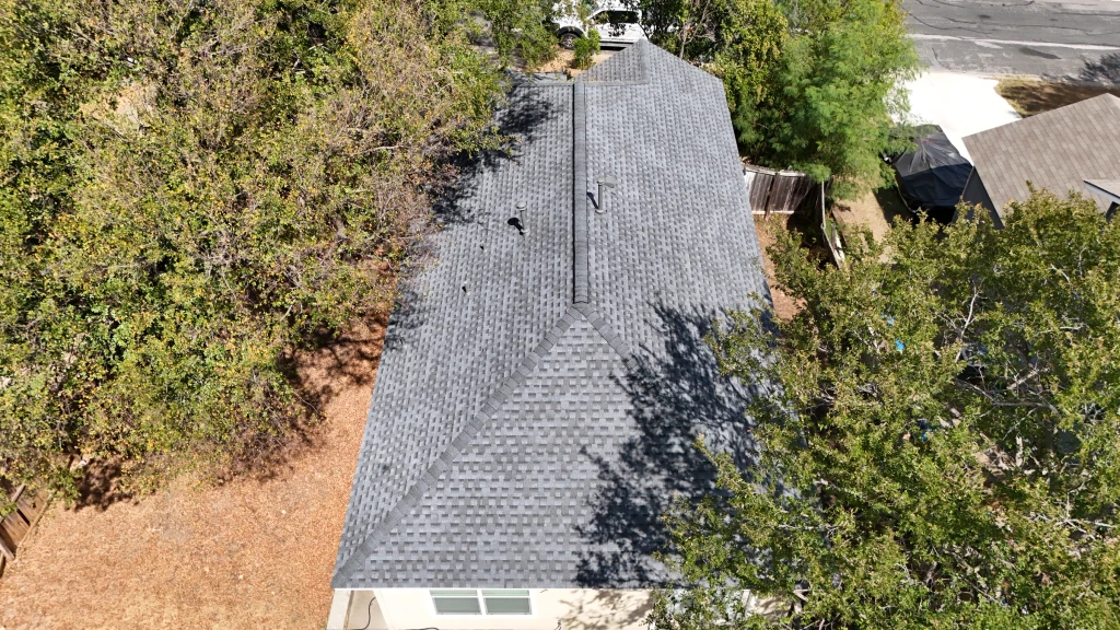 Rear aerial view of the finished Austin shingle roof, showing the hip roof and long ridge vent.