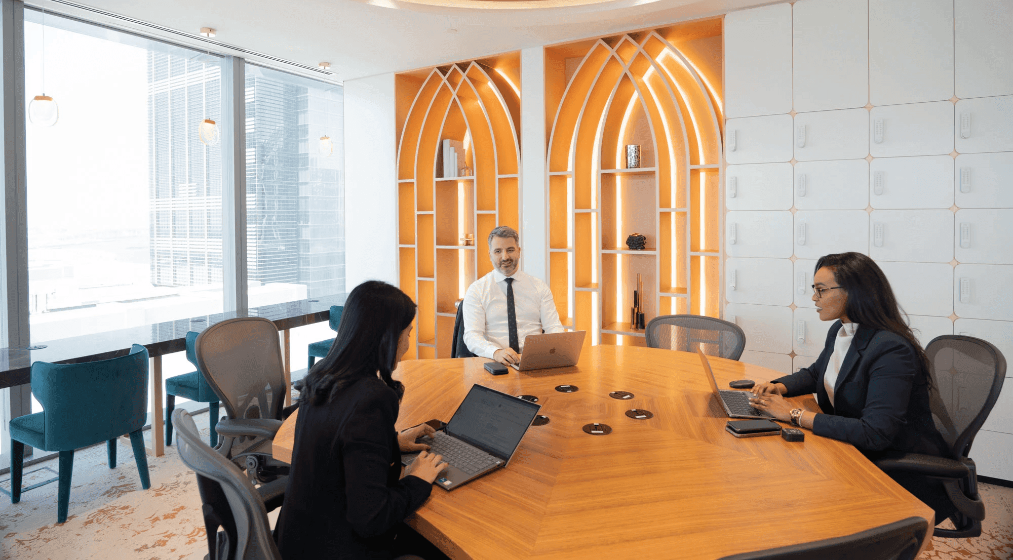 يجلس ثلاث أفراد على طاولة في قاعة اجتماعات المركز التنفيذي في الرياض.