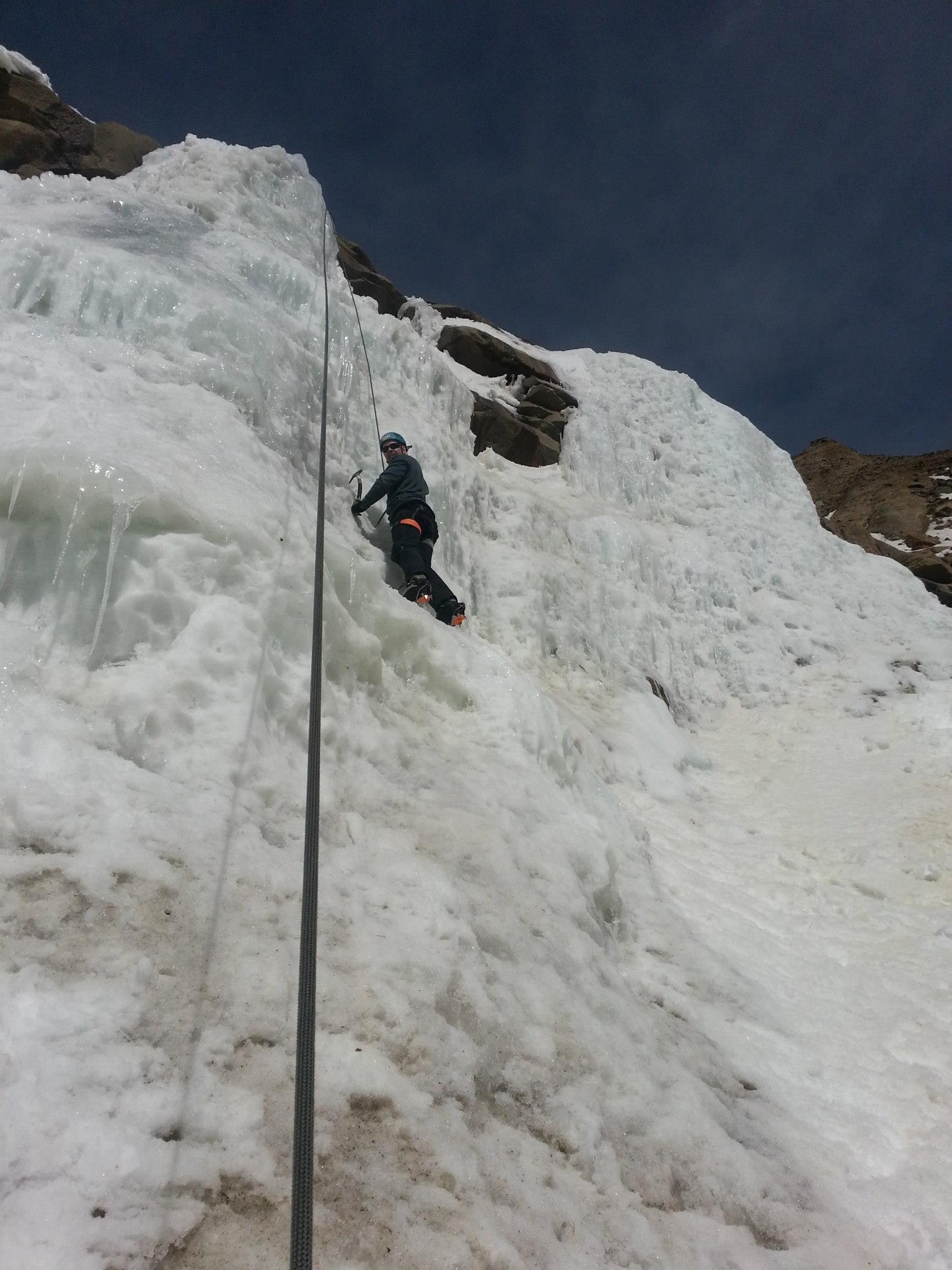 Ice climber looks down as they near the top of ice curtain in Clear Creek
