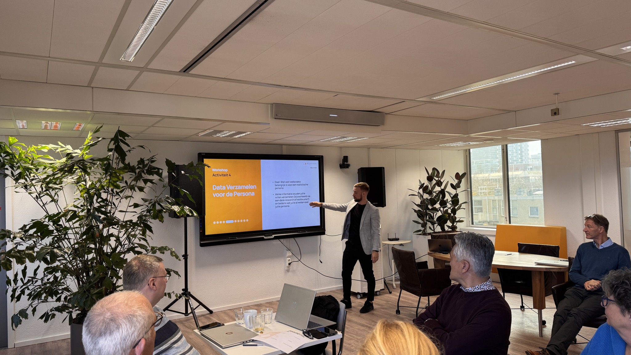 Four diverse professionals collaboratively working on a laptop, with one person pointing at the screen while others observe.