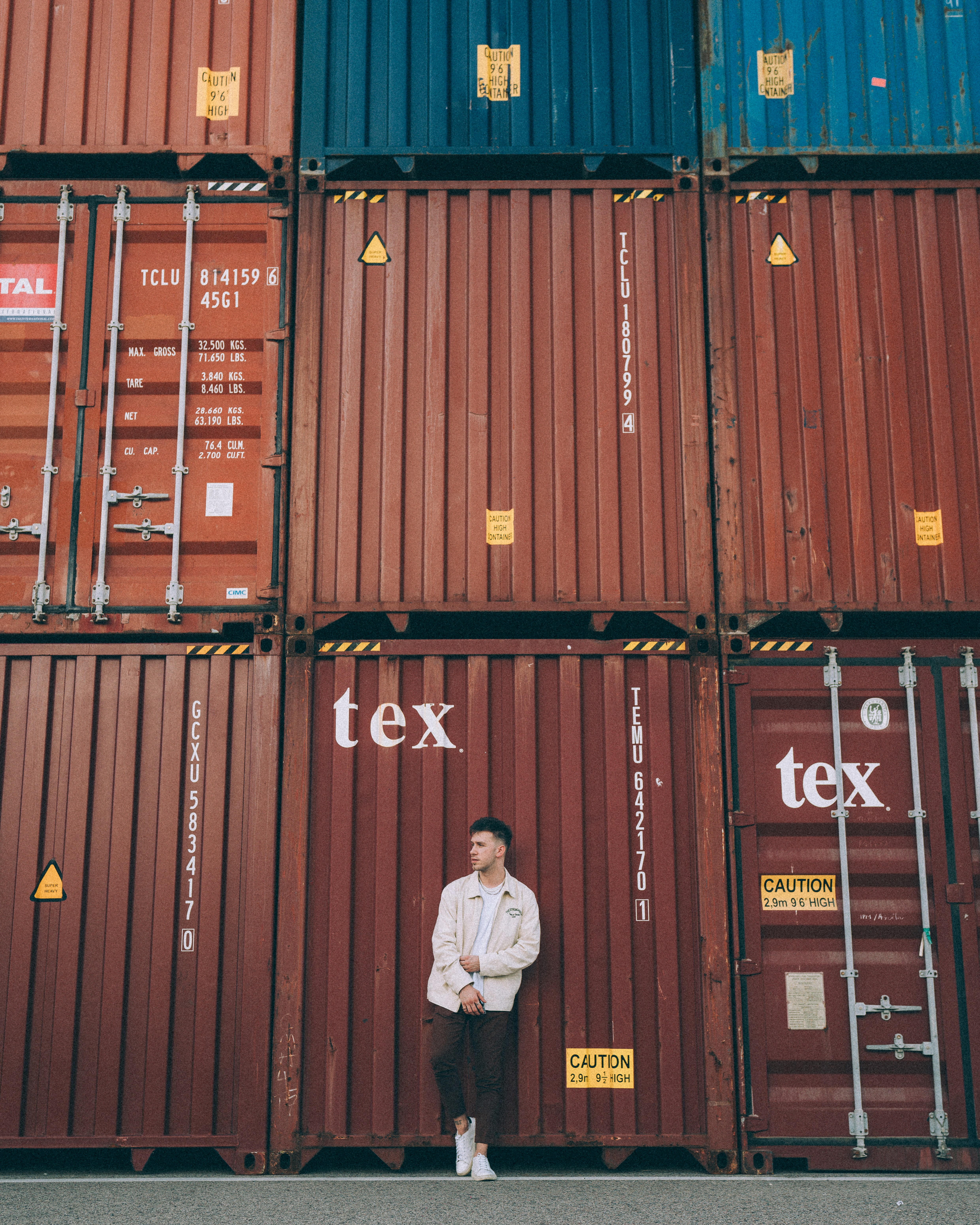 a man standing in front of a stack of shipping containers