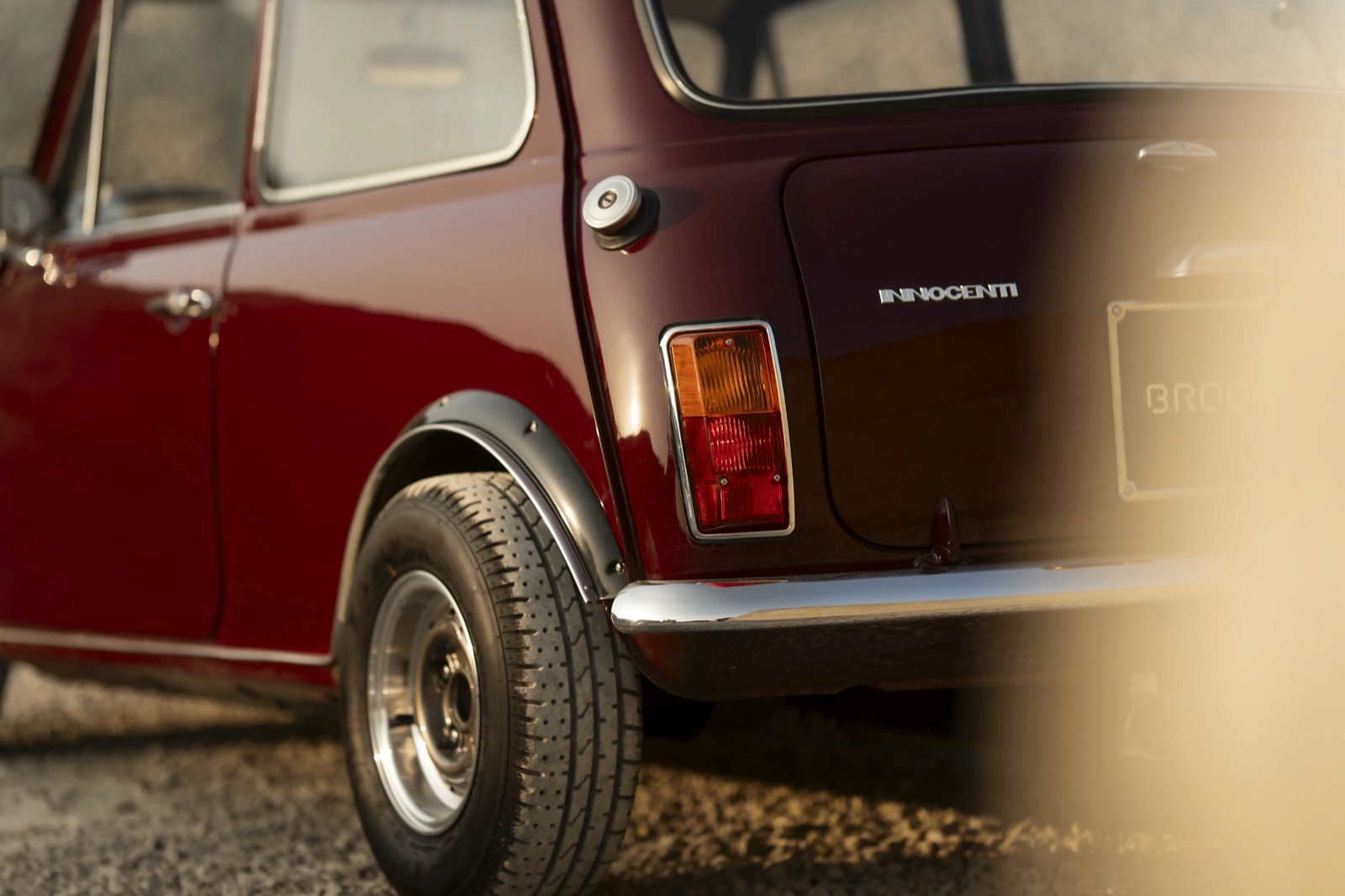 Close-up of the rear of a maroon vintage car, showcasing its classic design and wheel.