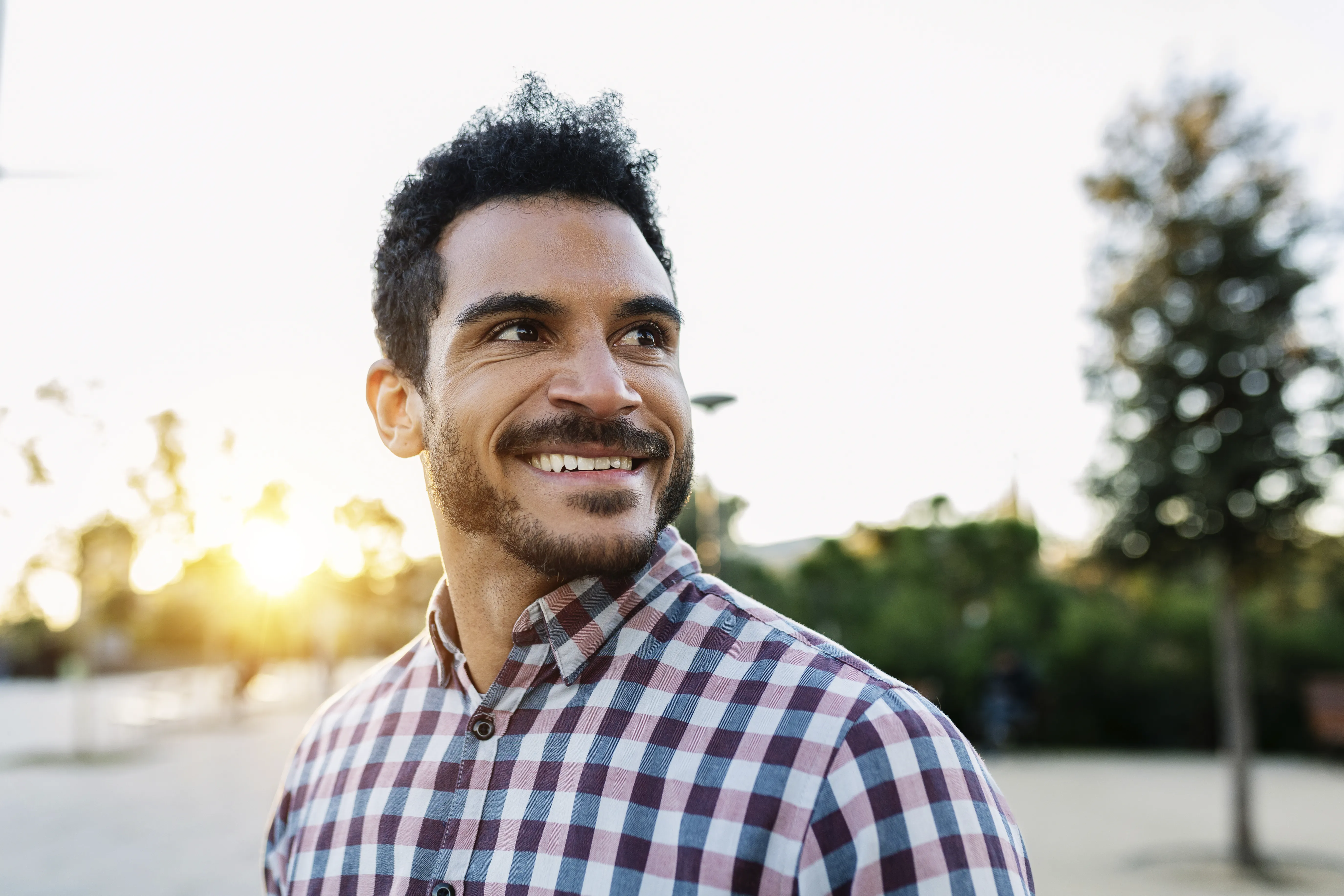 Man in flannel shirt smiling in a parking lot