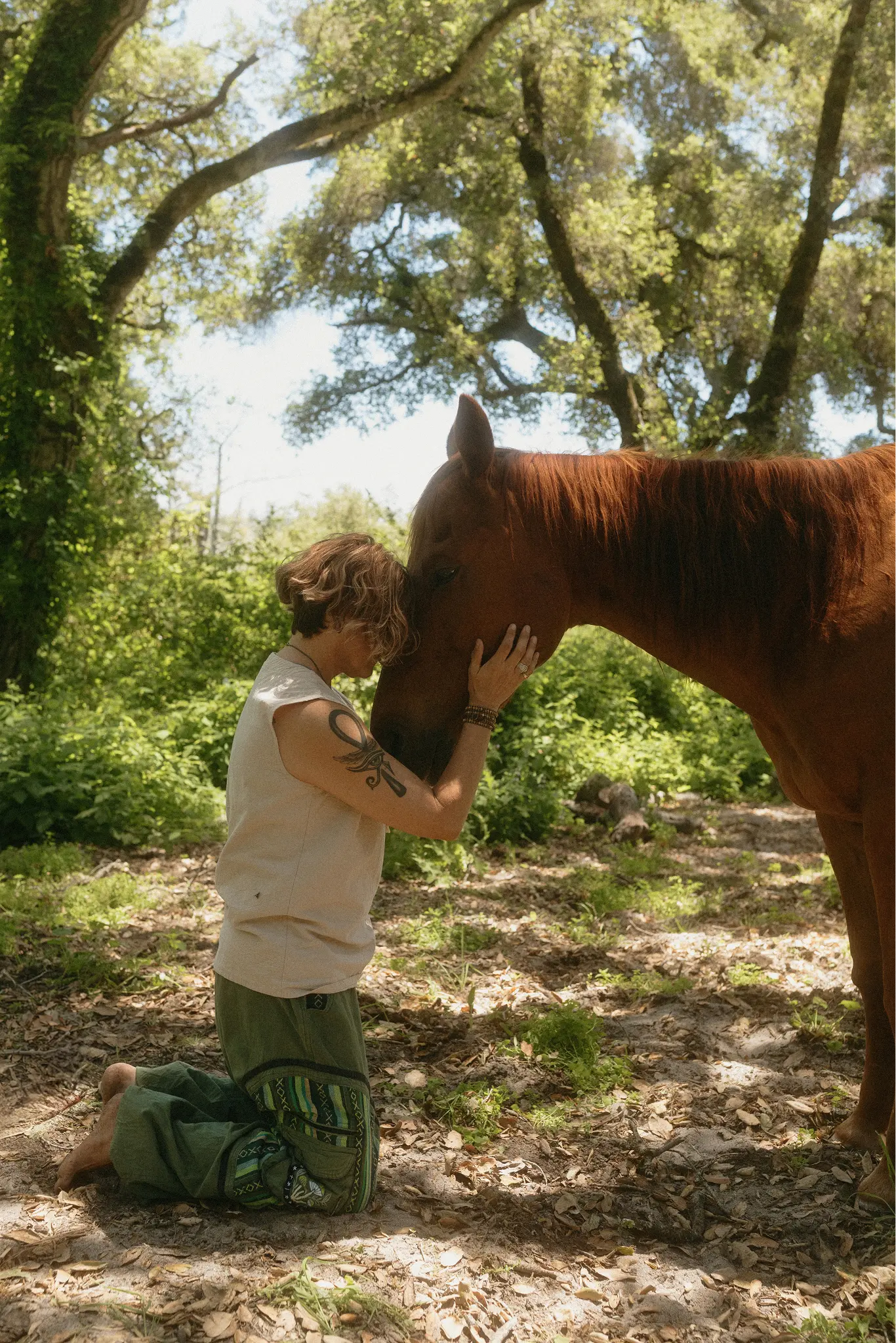 Sonia pressing her forehead tenderly against her horse Corona in a sunlit forest