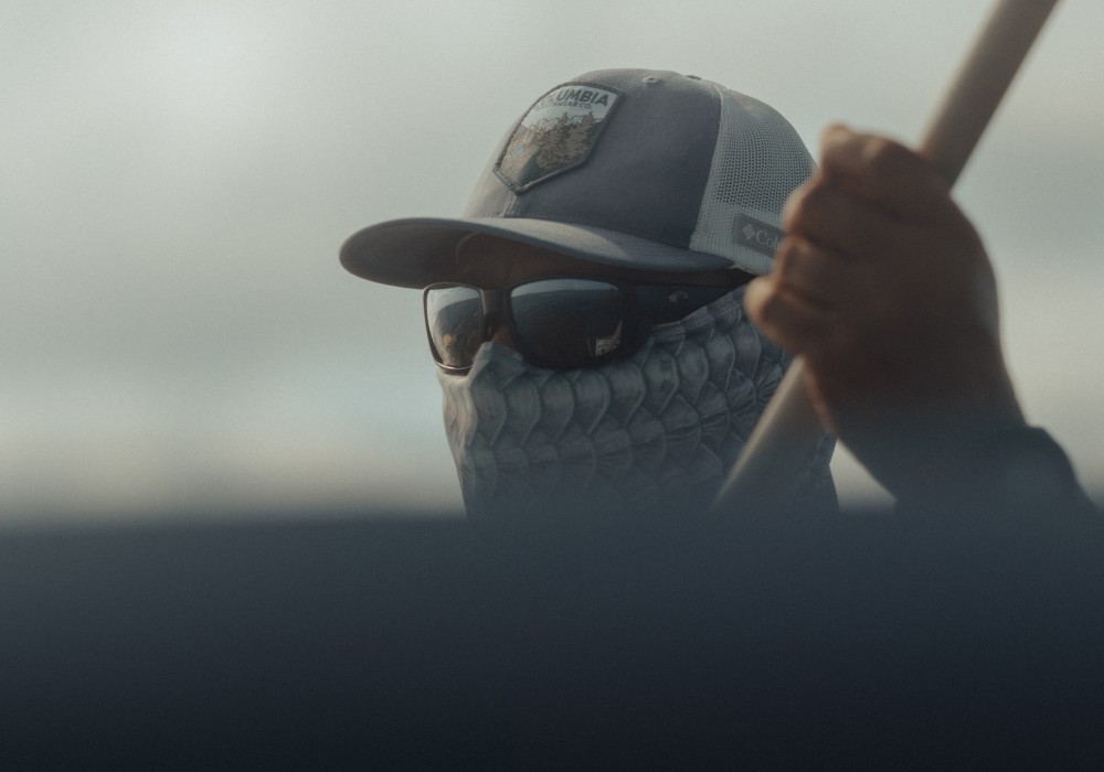 Tight crop portrait of Marlon Leslie with a push pole in his hand, wearing sunglasses and a cap