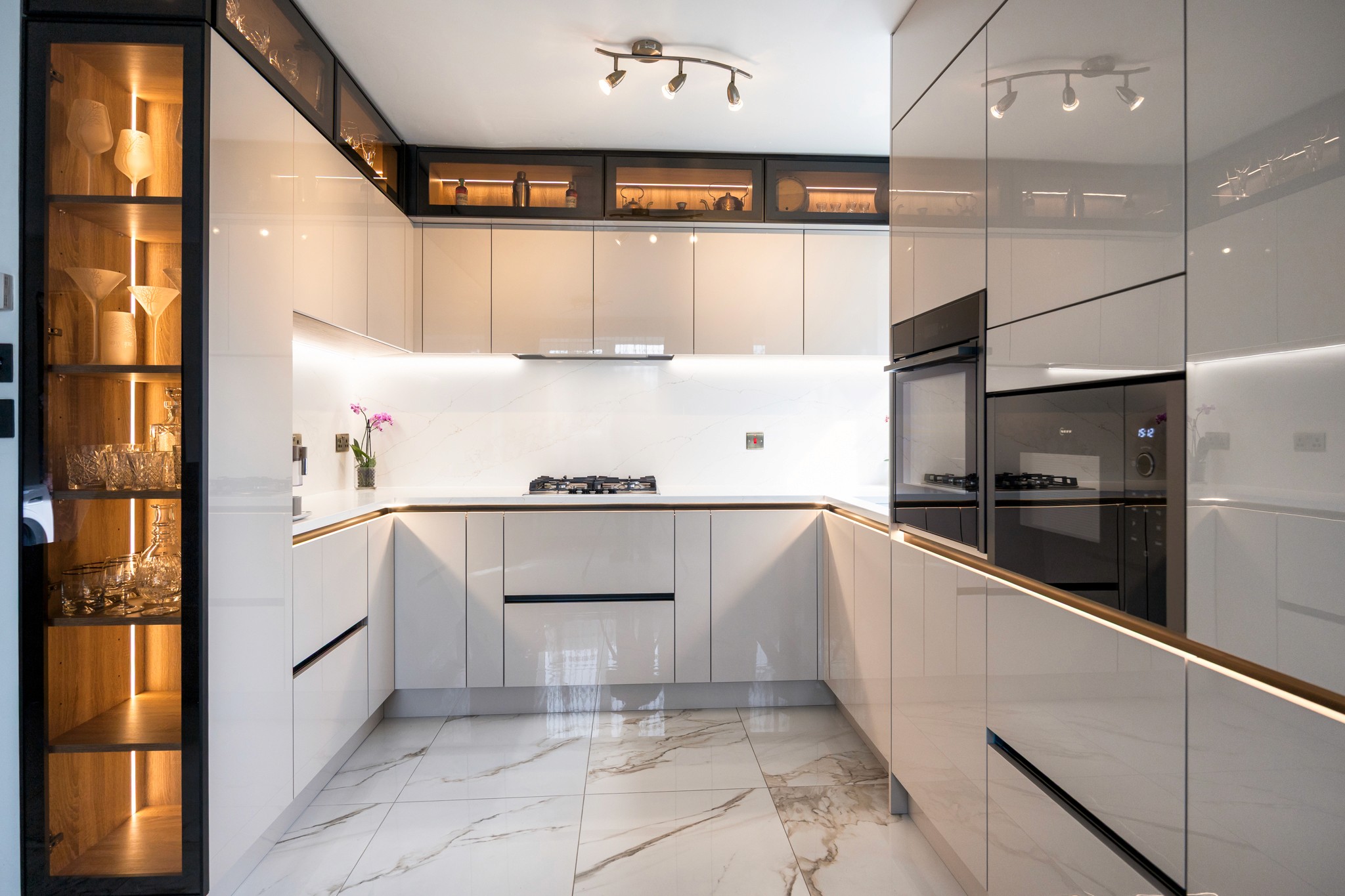 Modern two-story home with large glass windows, warmly lit interiors, and a balcony. Surrounded by trees and a manicured lawn at dusk. Cozy ambiance.