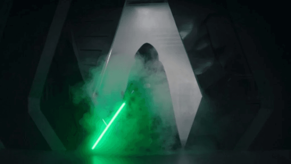 A silhouette of a figure holds a green lightsaber against a dark, misty background with a prominent emblem.