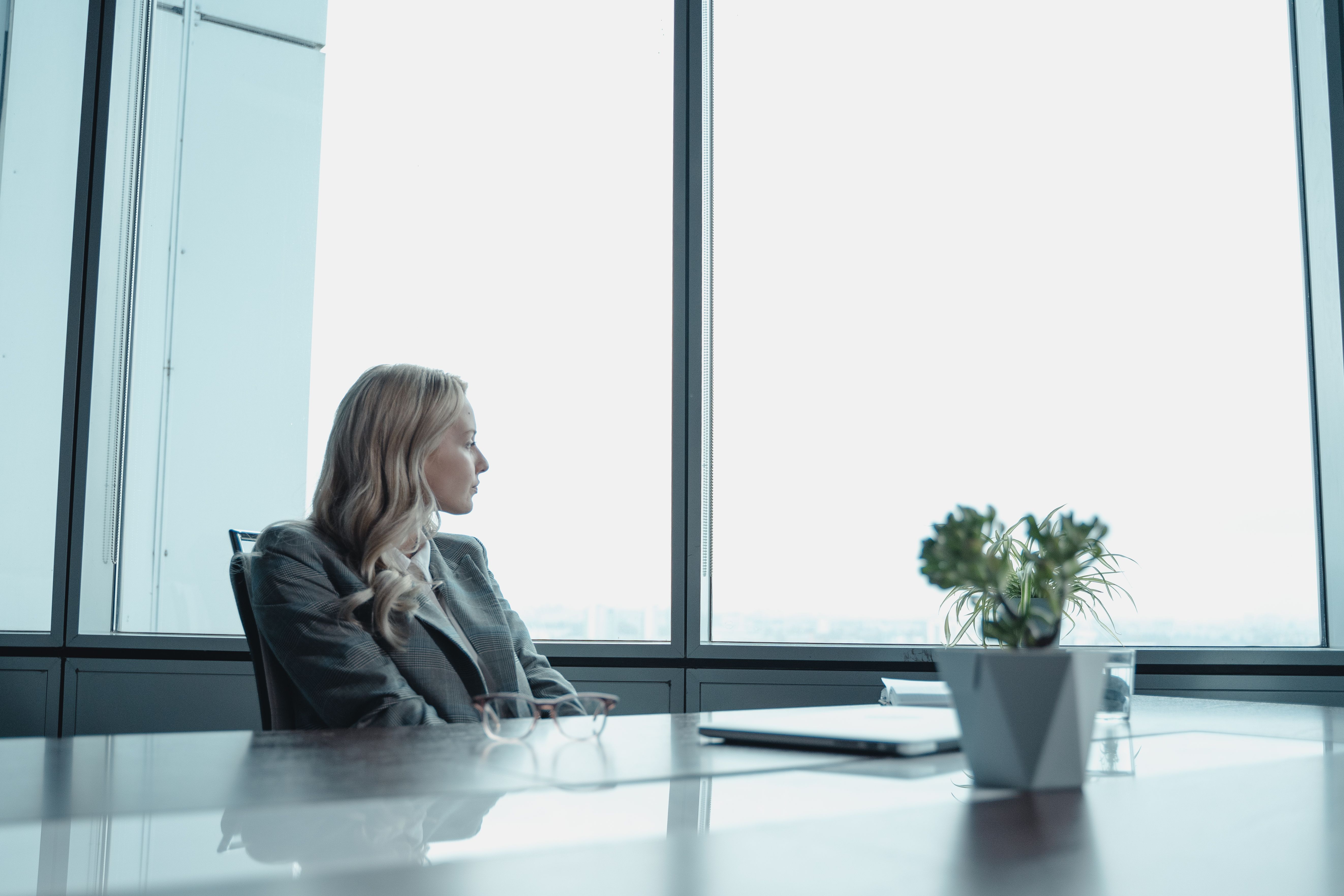 a-businesswoman-in-a-suit-looking-out-the-window-of-a-contemporary-office-with-a - tima-miroshnichenko (pexels)