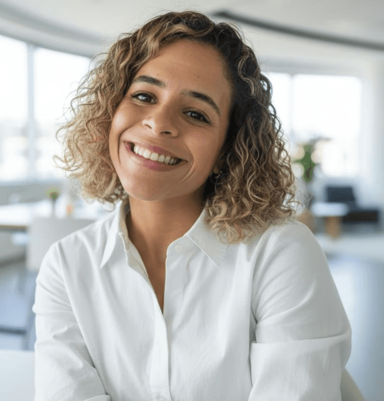 Smiling woman in a brown blazer against a warm orange background, exuding confidence and approachability.